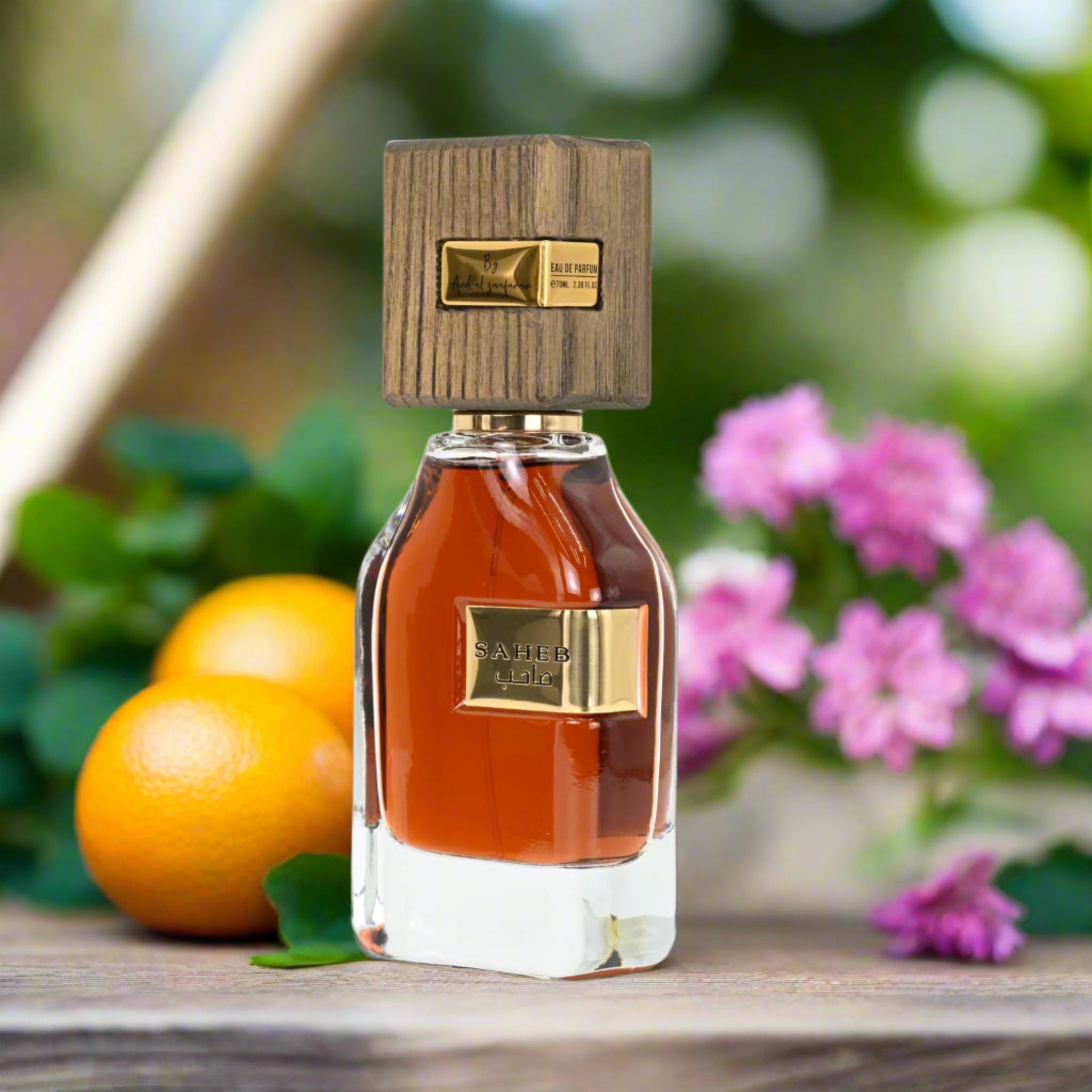 Perfume bottle with wooden cap and gold accents on a table with fruits and flowers in the background