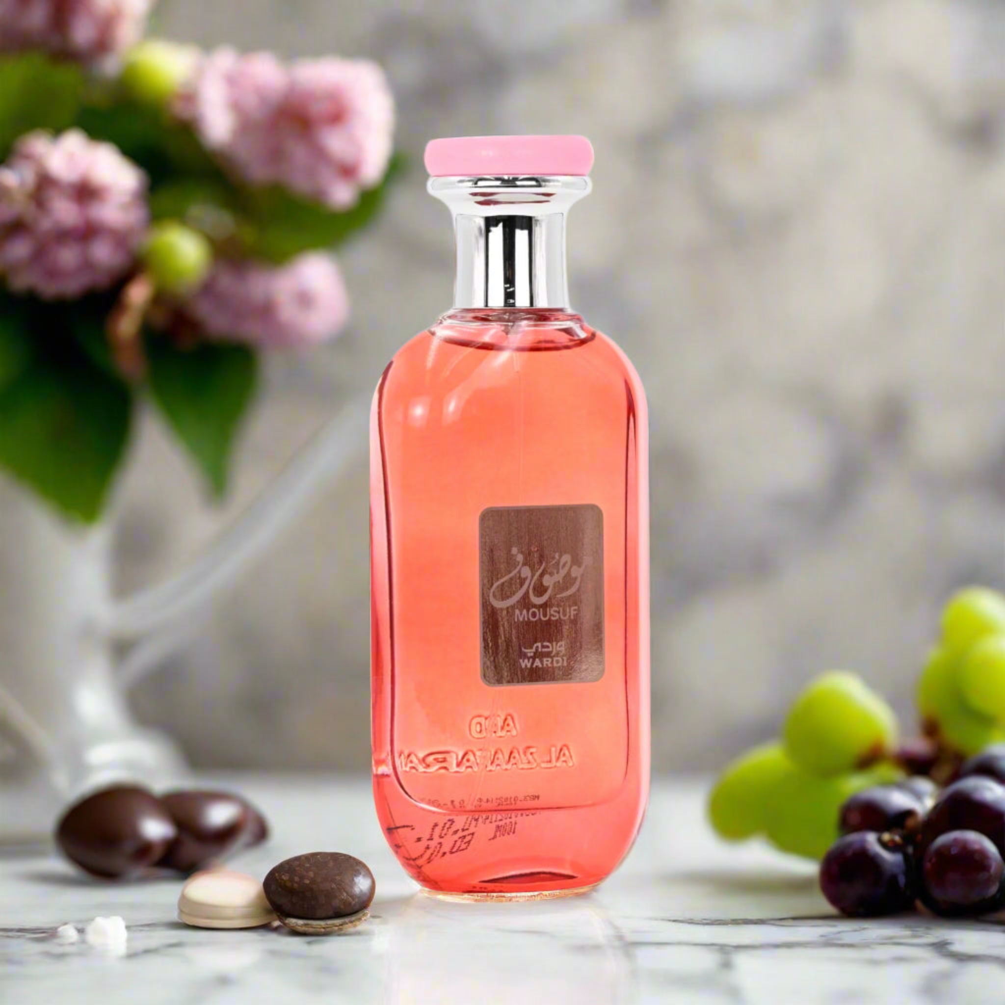 Pink perfume bottle with a floral and fruit background