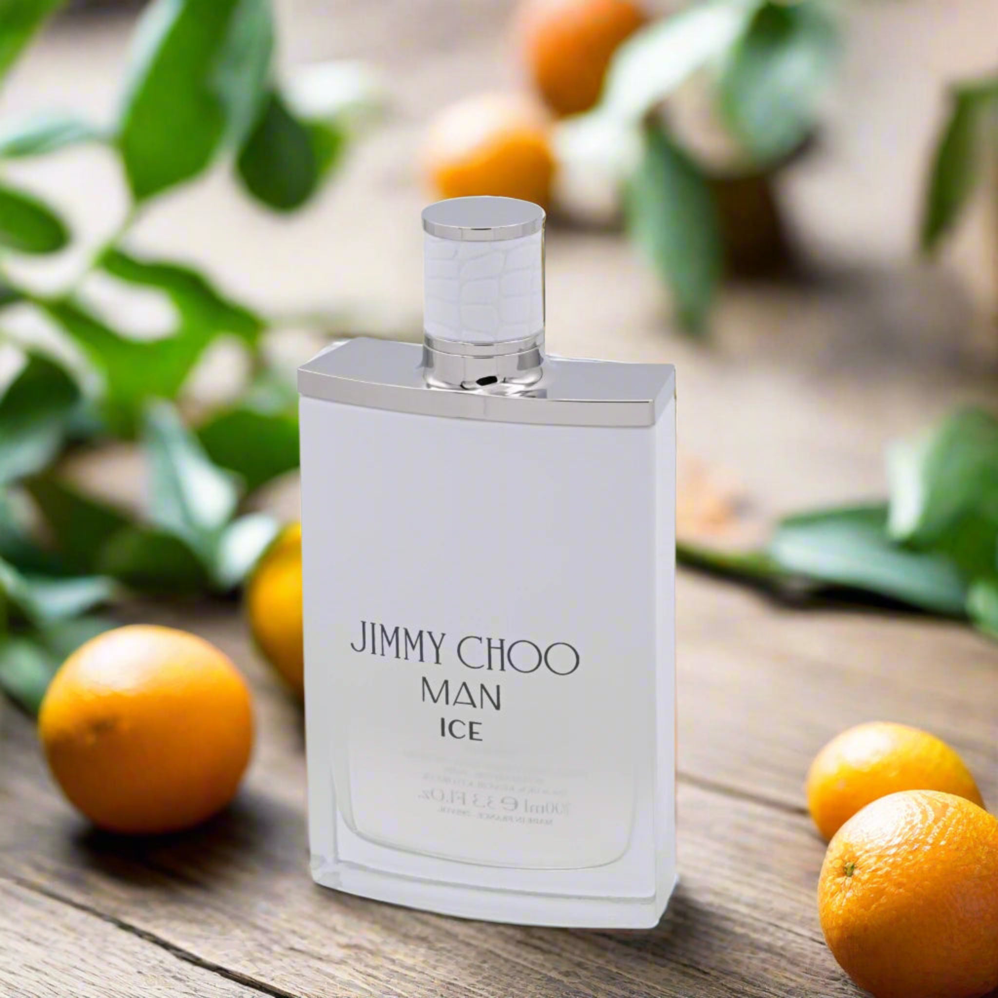 Jimmy Choo Man Ice perfume bottle on a wooden surface with oranges and leaves.