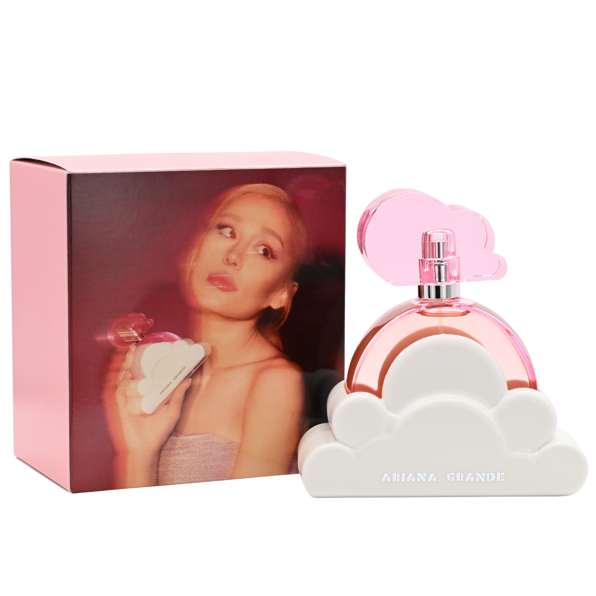 Perfume bottle with pink cap and cloud design next to packaging featuring a woman's face.