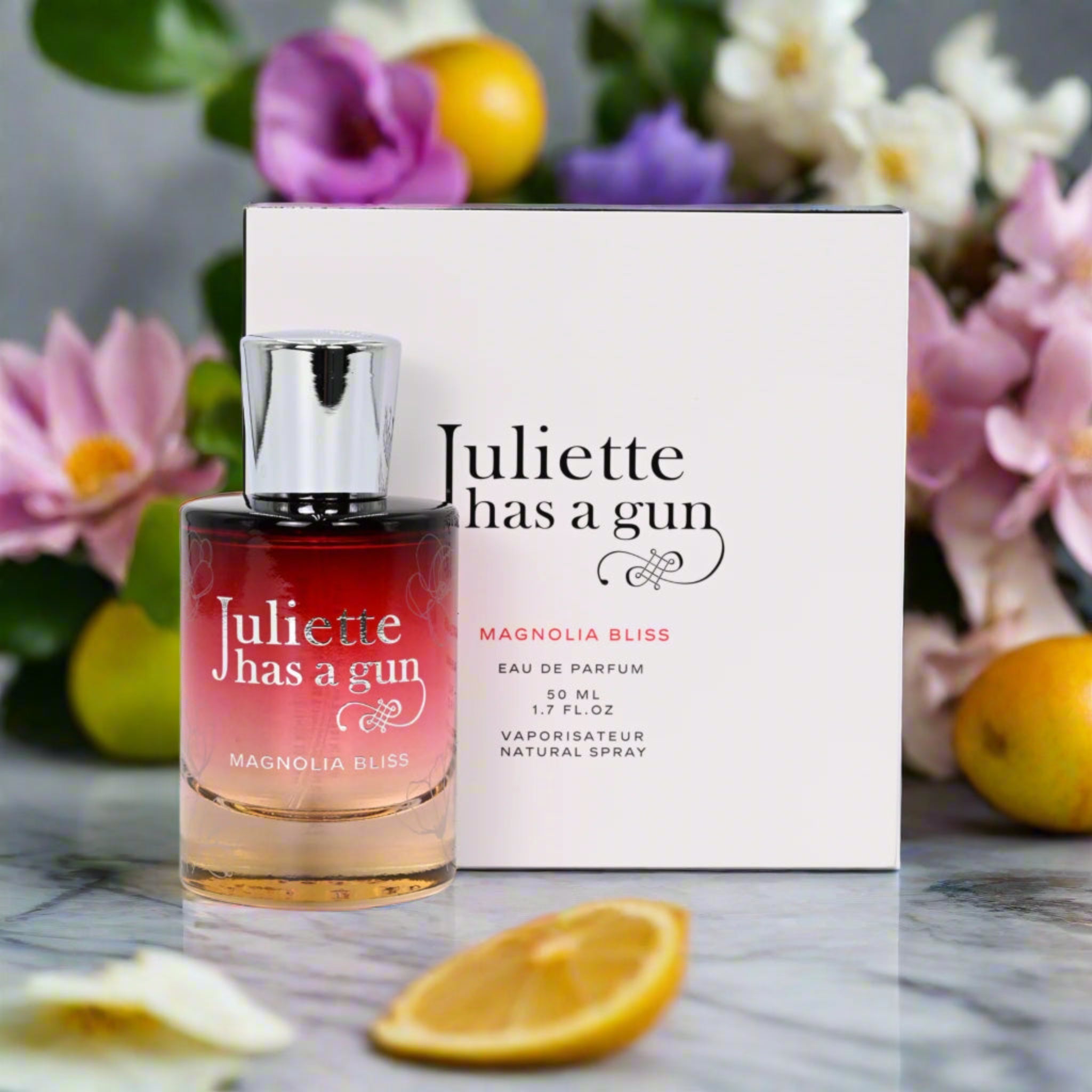Perfume bottle and packaging of 'Juliette has a gun' with flowers and lemons in the background
