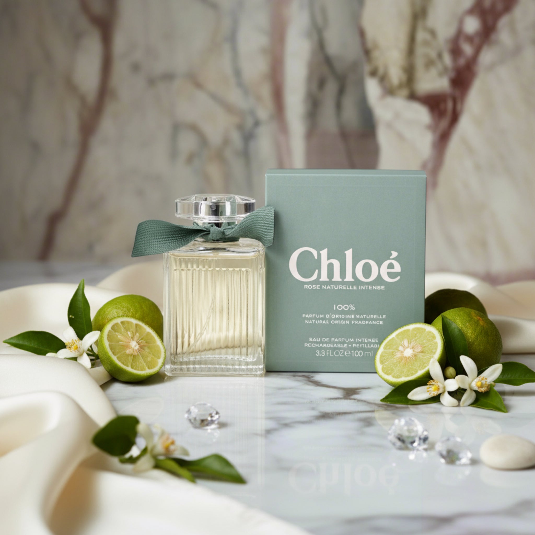 Rose Naturelle Intense perfume bottle  and box on a luxurious background with Bergamots and Neroli