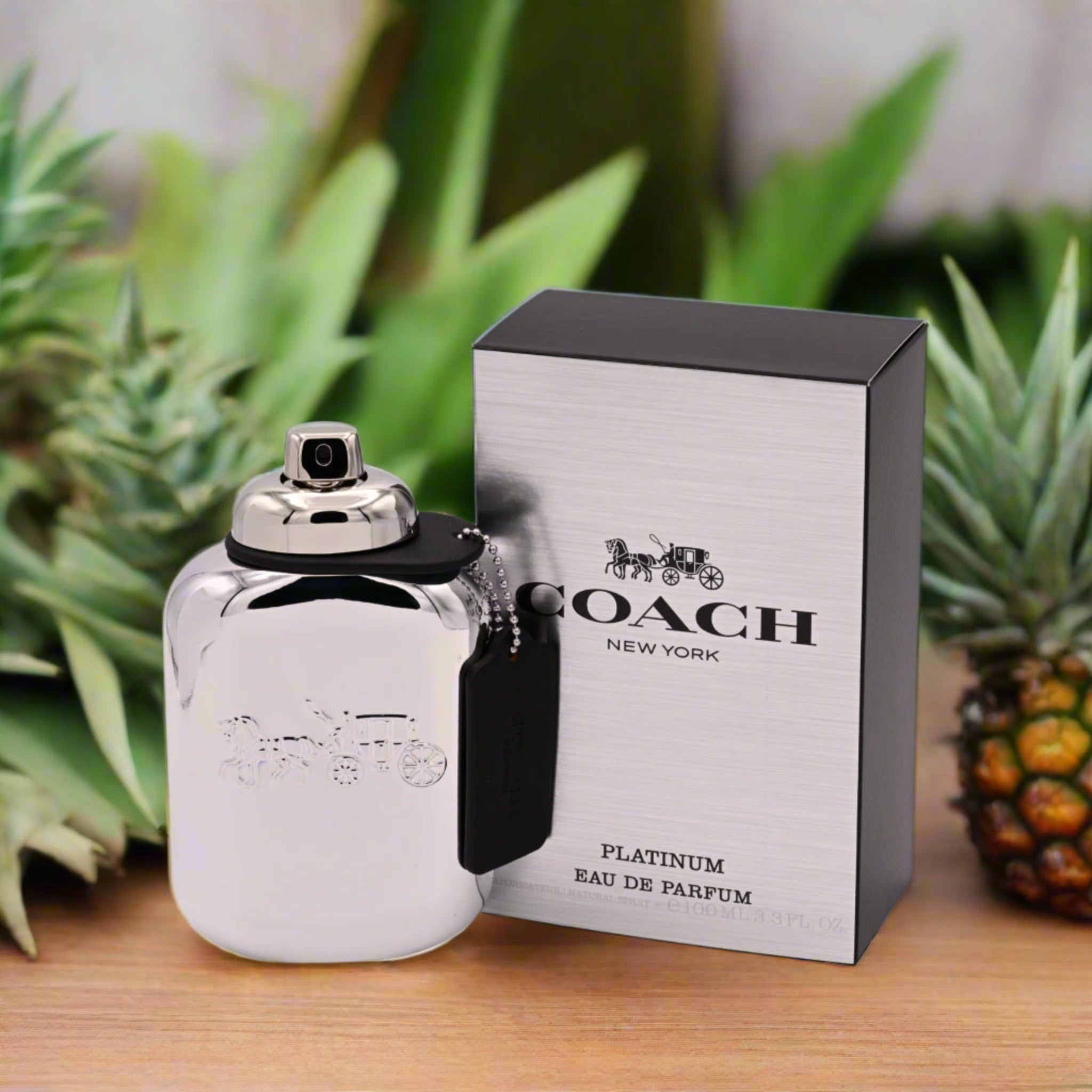 Coach New York Platinum Eau de Parfum bottle and packaging with a pineapple and plants in the background