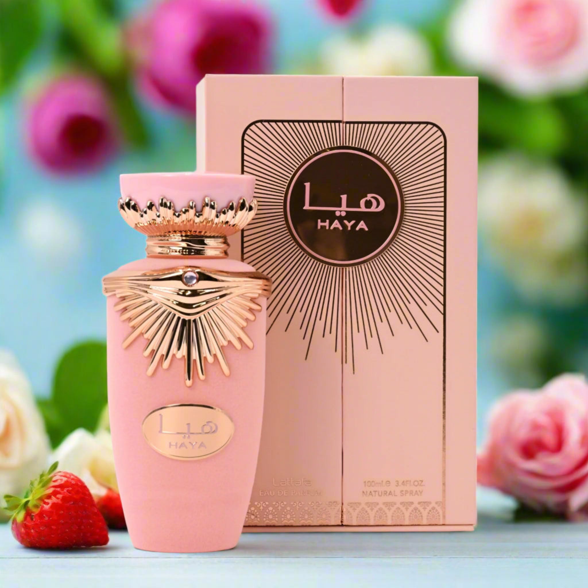Pink Haya perfume bottle and box with flowers in the background