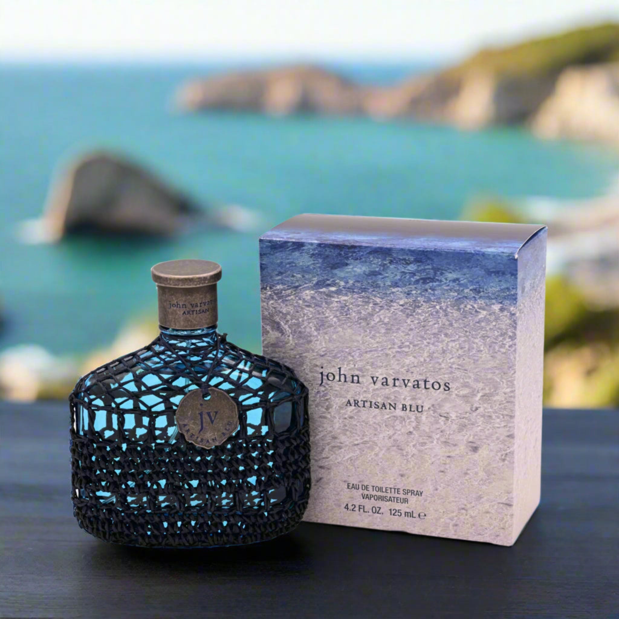 John Varvatos Artisan Blu perfume bottle and packaging with a scenic background