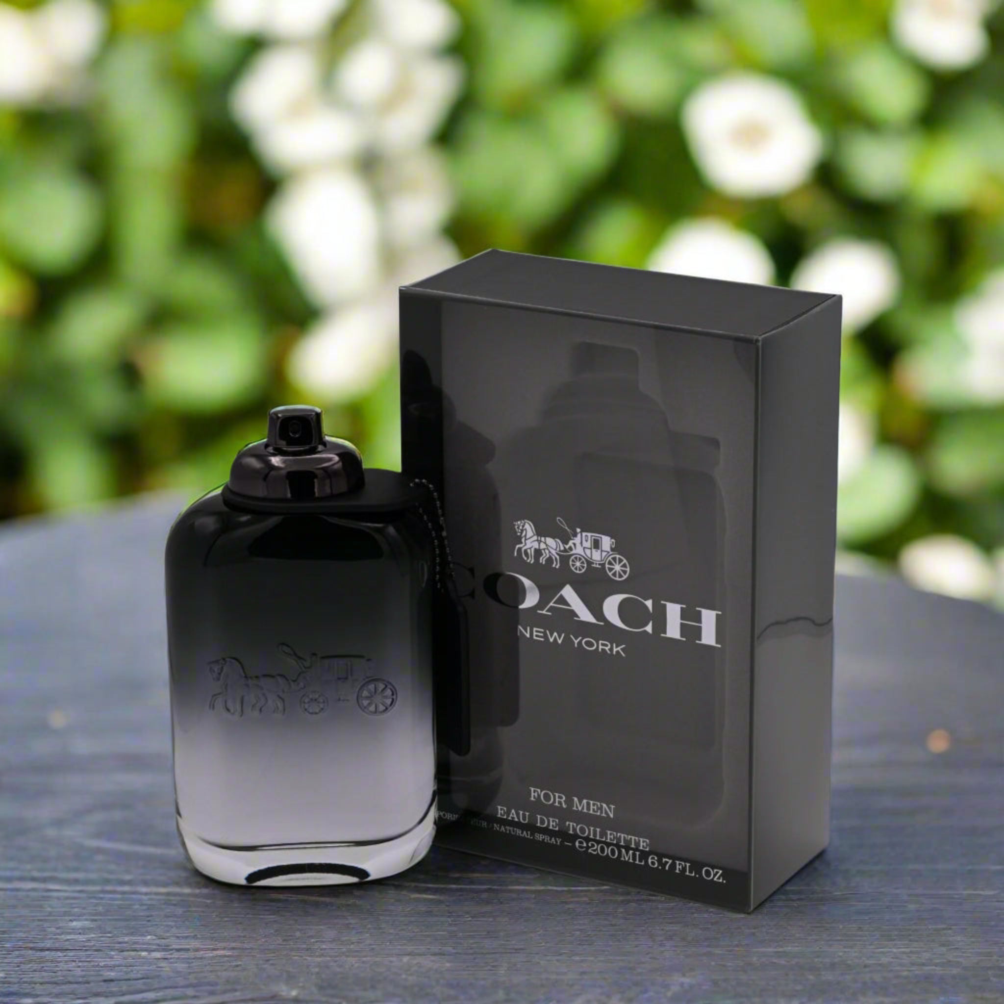 Coach New York men's perfume bottle and packaging on a wooden surface with a blurred green background