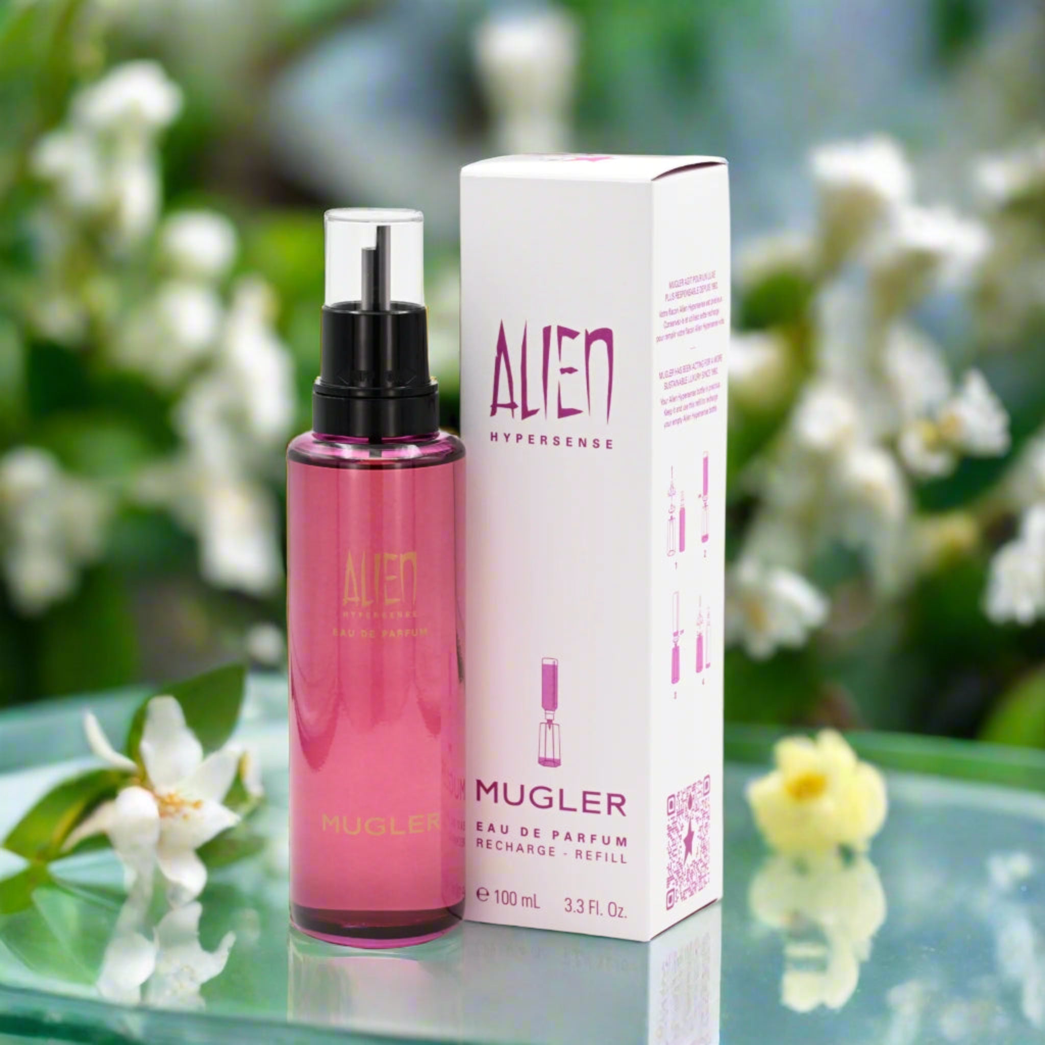Mugler Alien perfume bottle and packaging on a reflective surface with flowers in the background