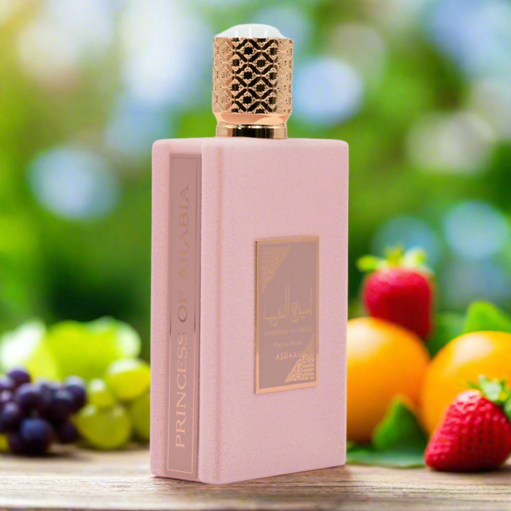 Pink perfume bottle with gold accents on a wooden surface with fruits in the background