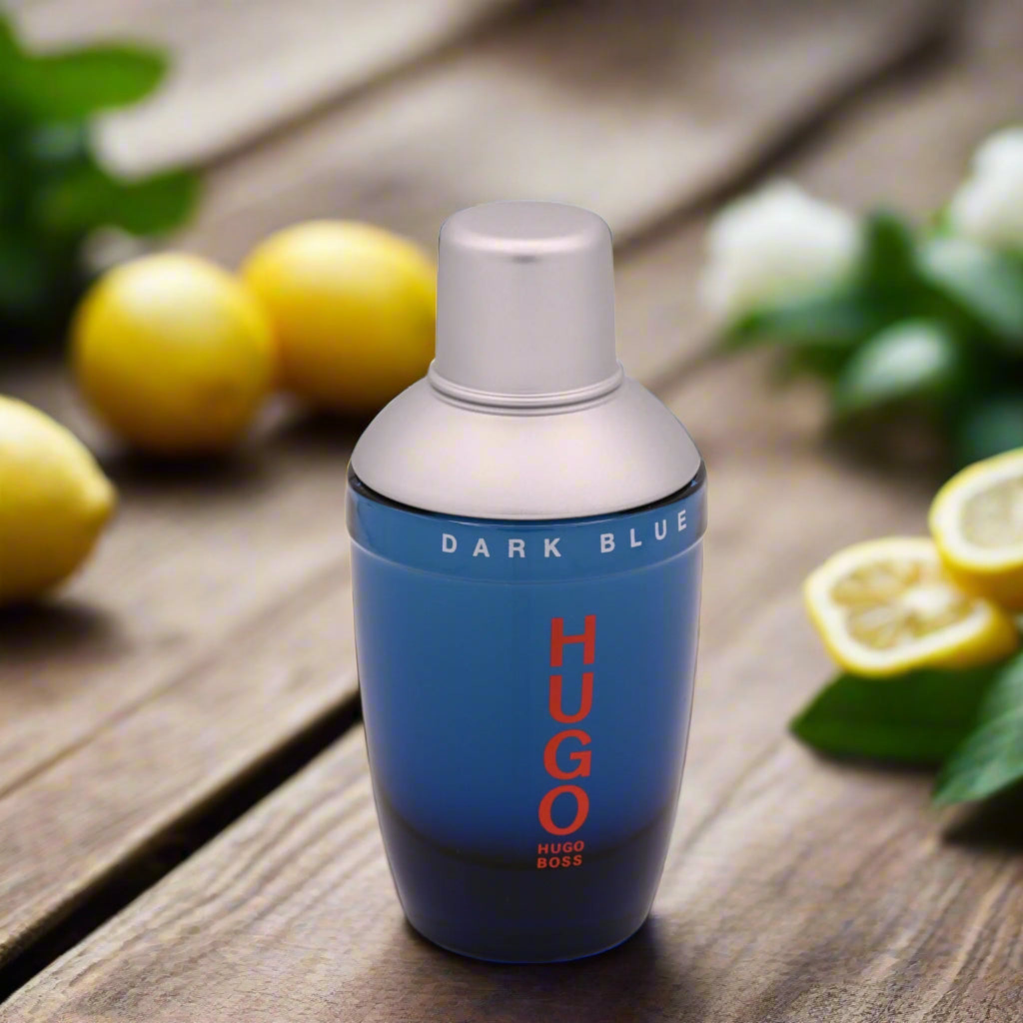 Hugo Boss Dark Blue perfume bottle on a wooden surface with lemons and leaves.