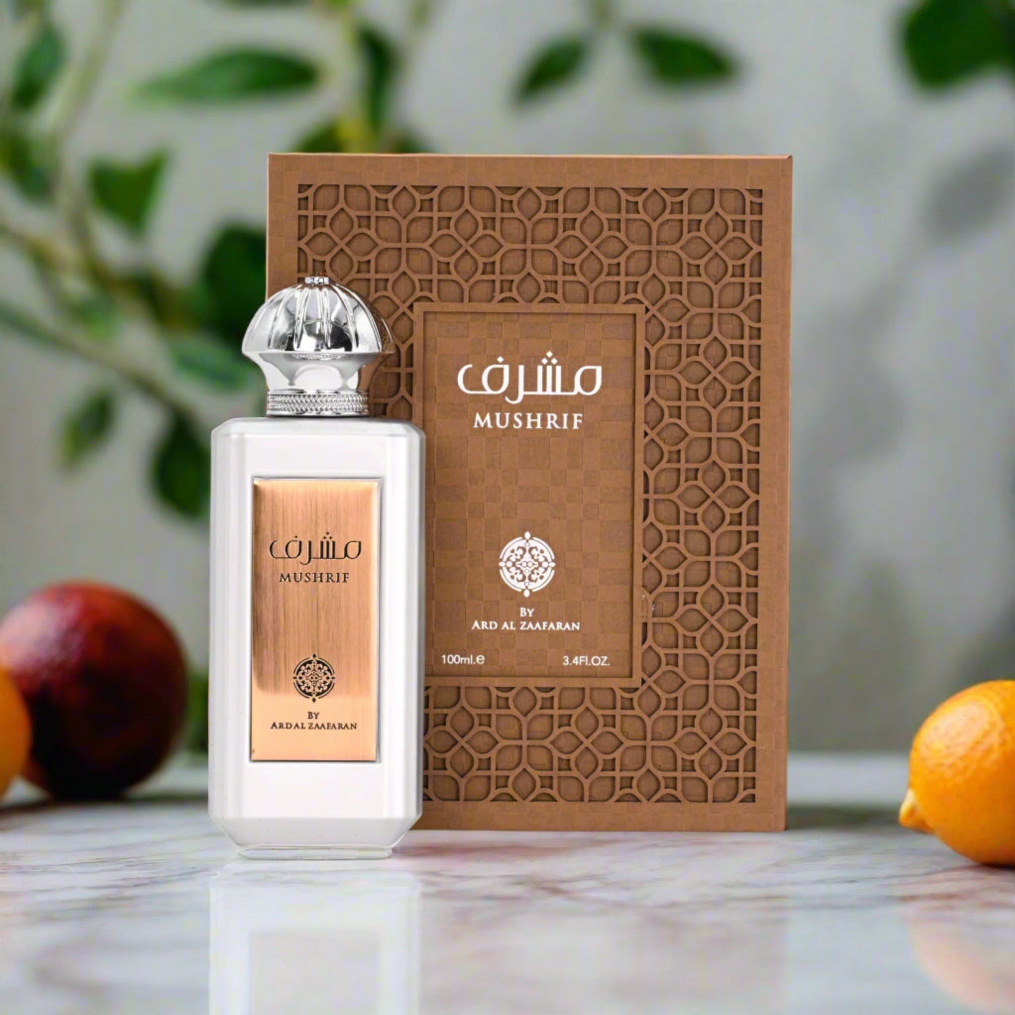 Mushrif perfume bottle and packaging on a reflective surface with fruits in the background