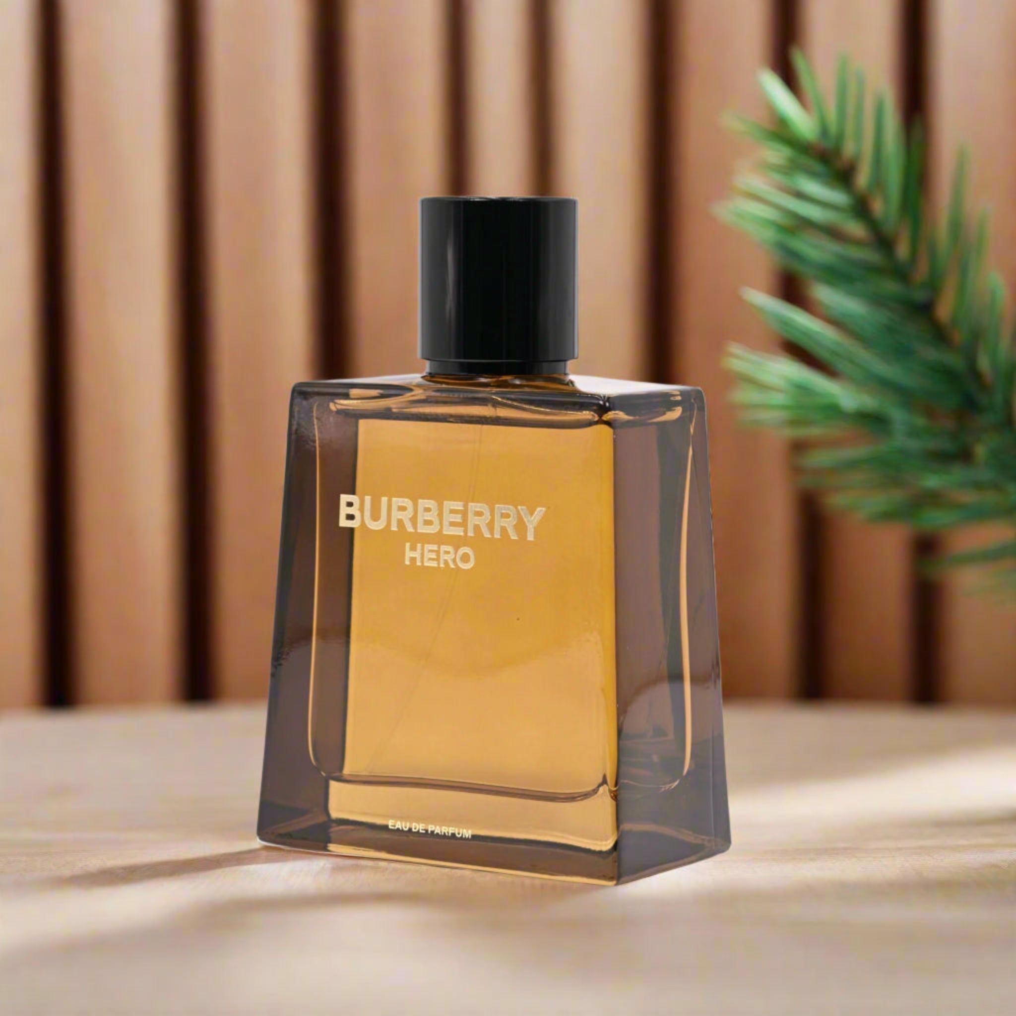 Burberry Hero perfume bottle on a wooden surface with a blurred plant in the background