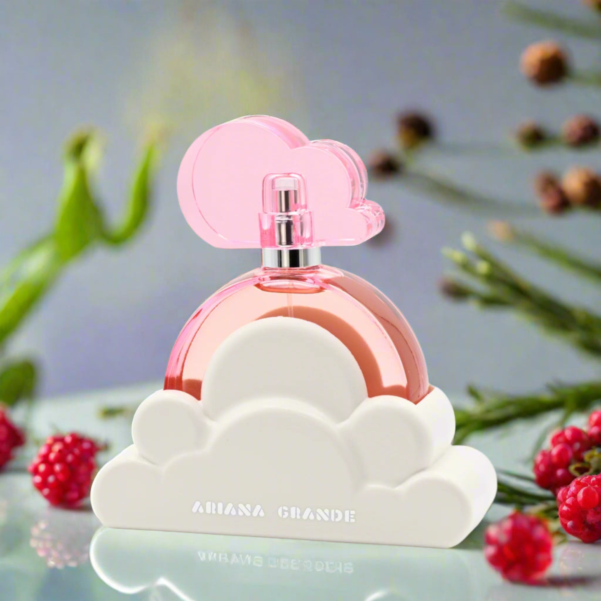 Perfume bottle with pink cap and cloud design on a reflective surface with berries and greenery in the background