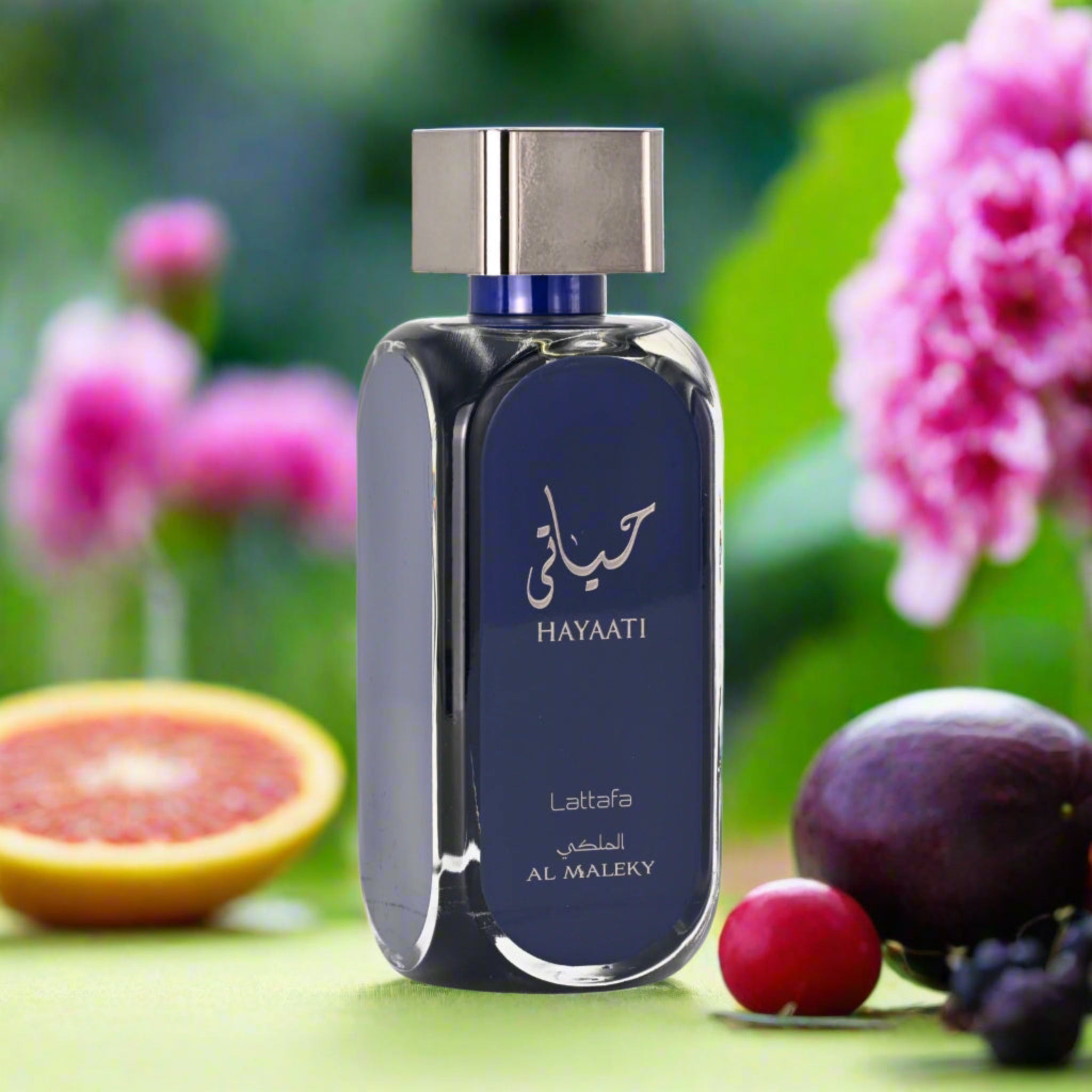 Perfume bottle with 'Hayaati' branding on a green background with fruits and flowers