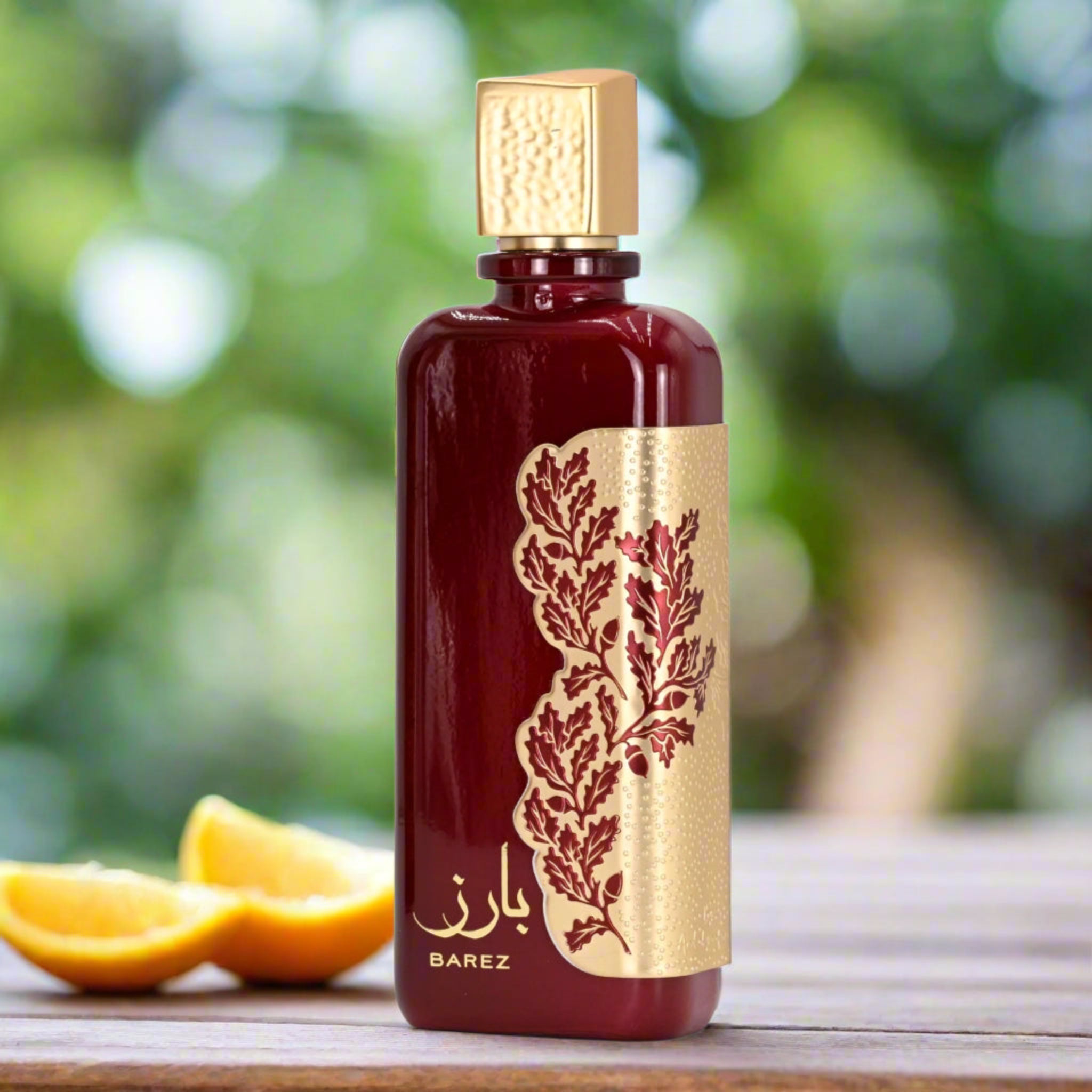 BAREZ perfume bottle with a gold cap and design on a wooden surface with oranges and a blurred green background