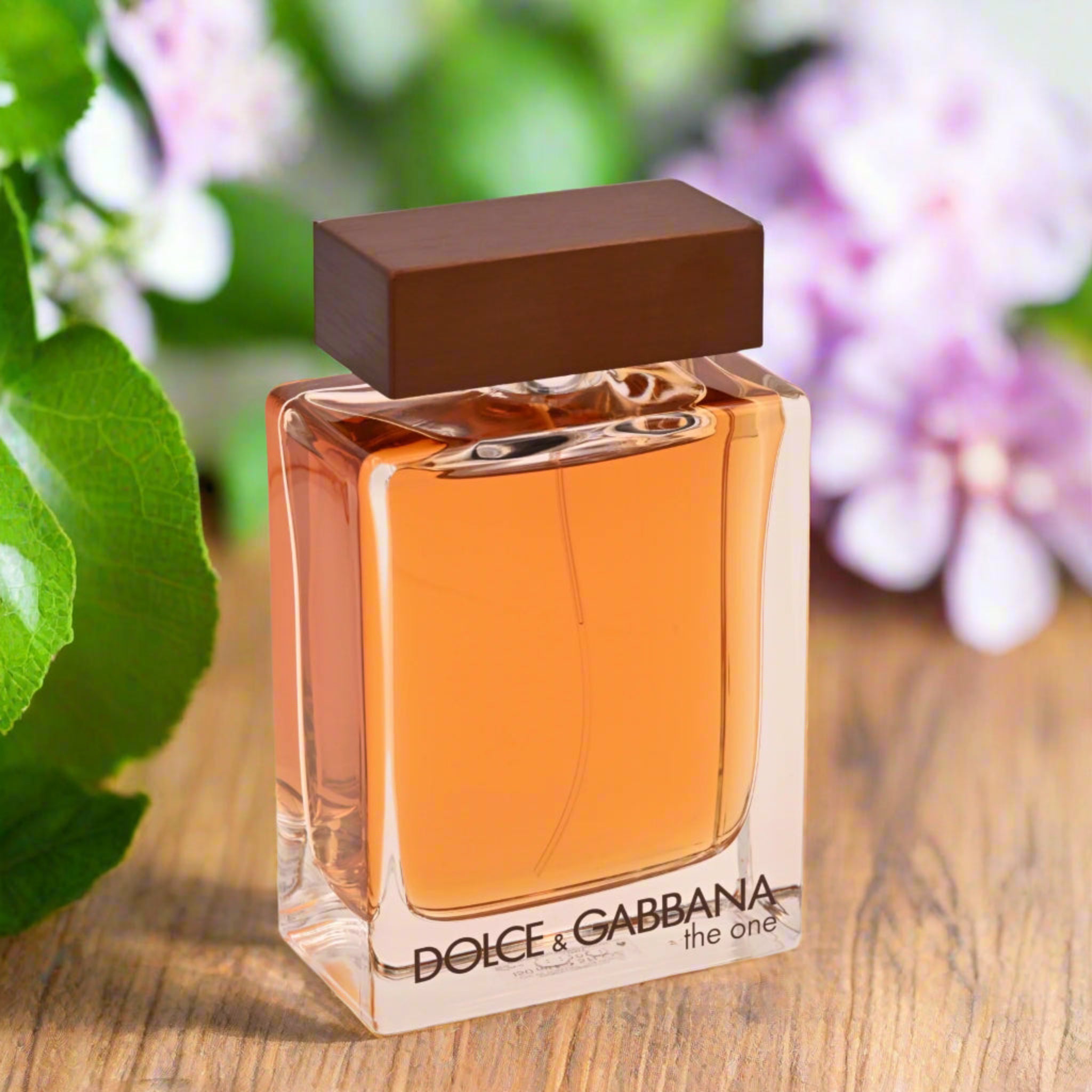 Dolce & Gabbana perfume bottle on a wooden surface with flowers in the background