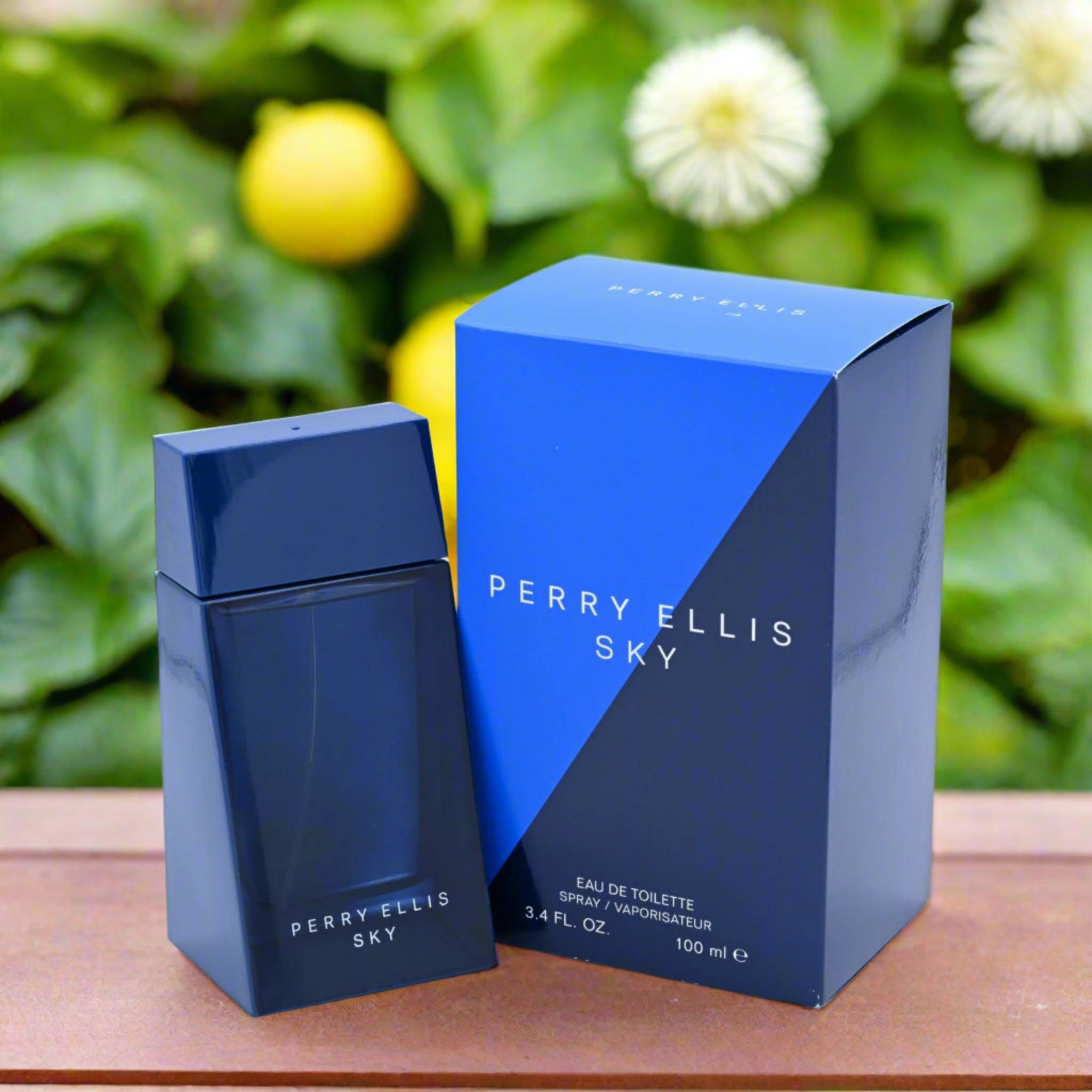 Perry Ellis Sky perfume bottle and packaging on a wooden surface with a green leafy background