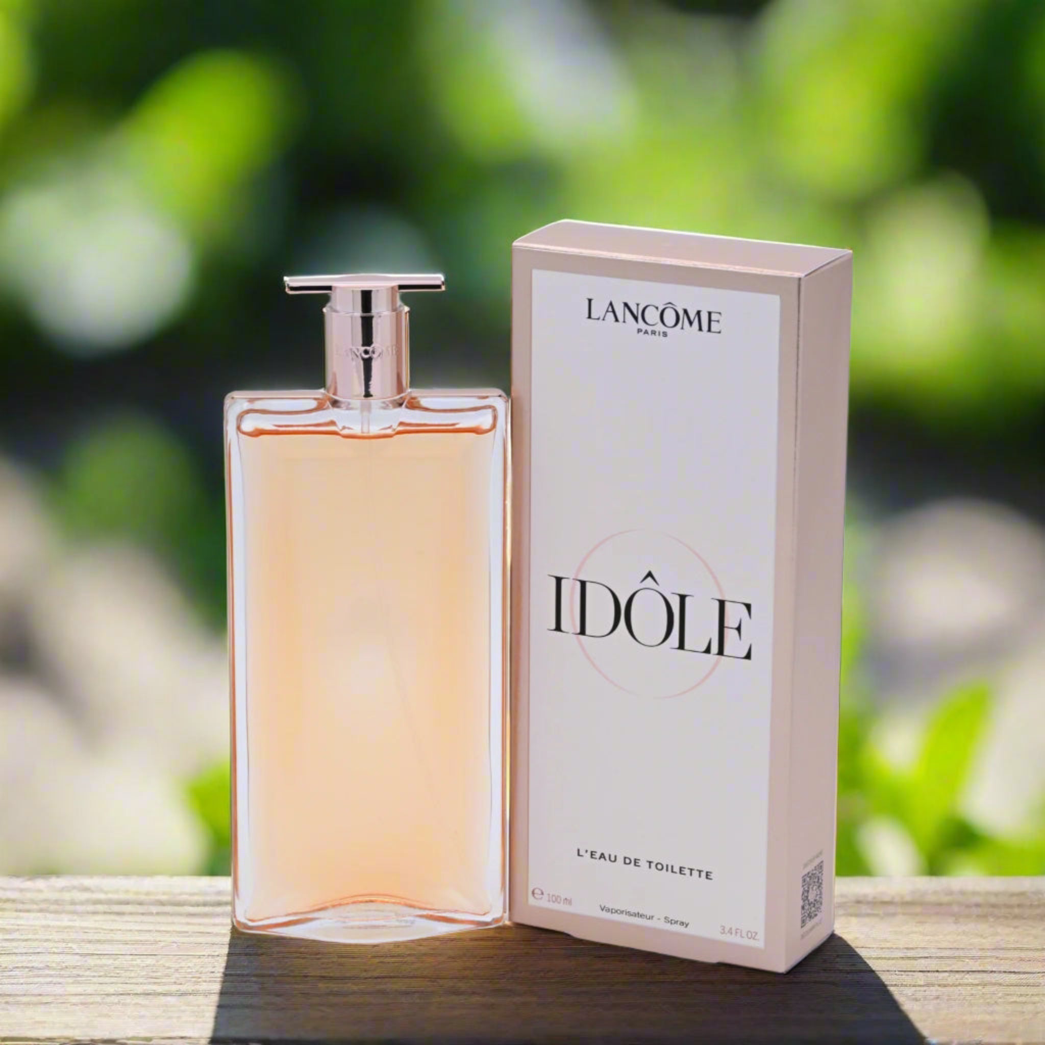 Lancème Idôle perfume bottle and packaging on a wooden surface with a blurred green background