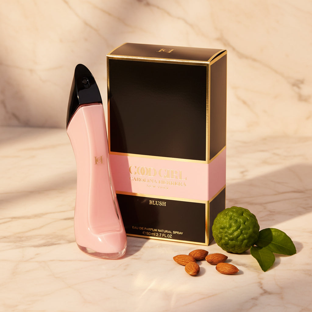 Pink perfume bottle with black cap next to a black box labeled 'Good Girl' on a beige marble surface.