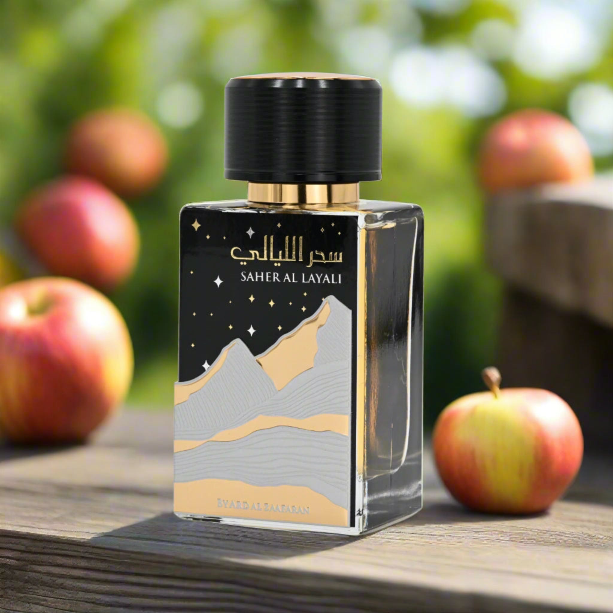 Perfume bottle with mountain design on a wooden surface with apples in the background