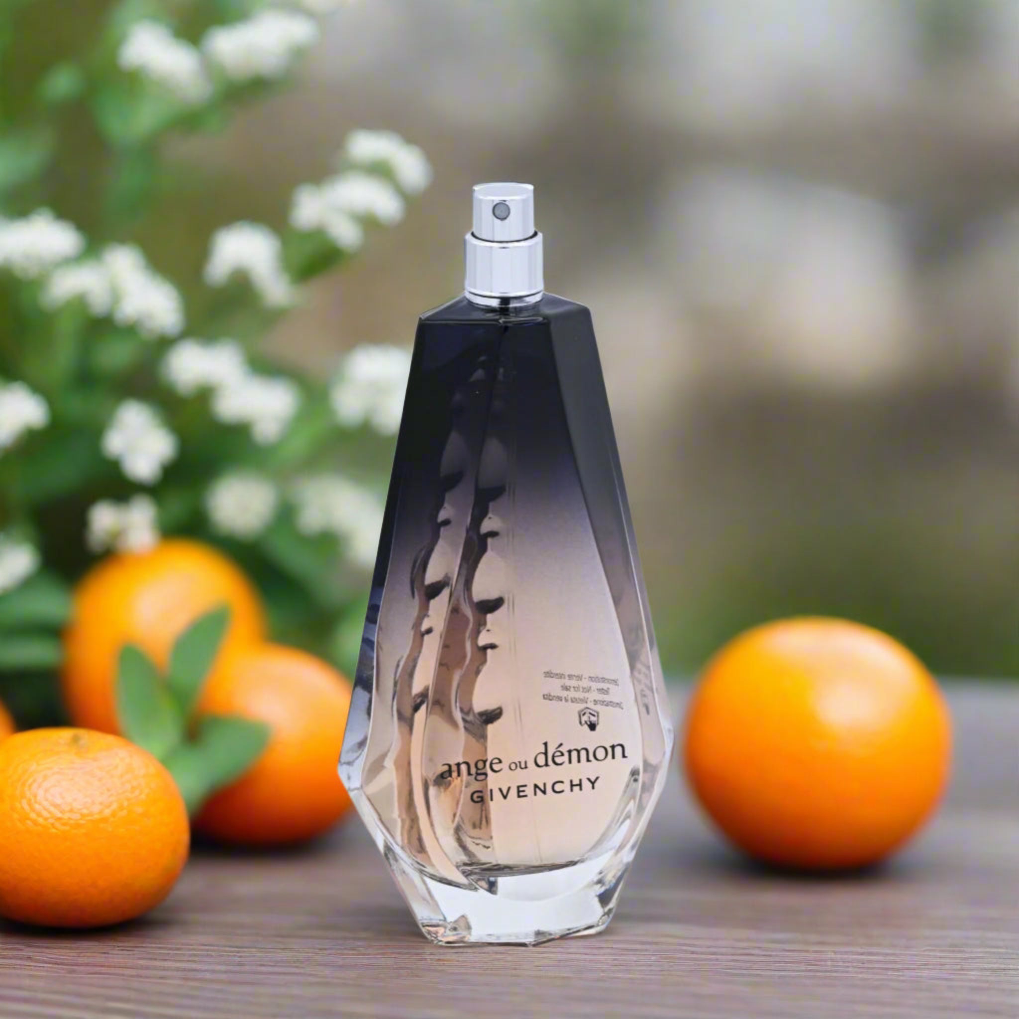Givenchy perfume bottle with oranges and flowers in the background