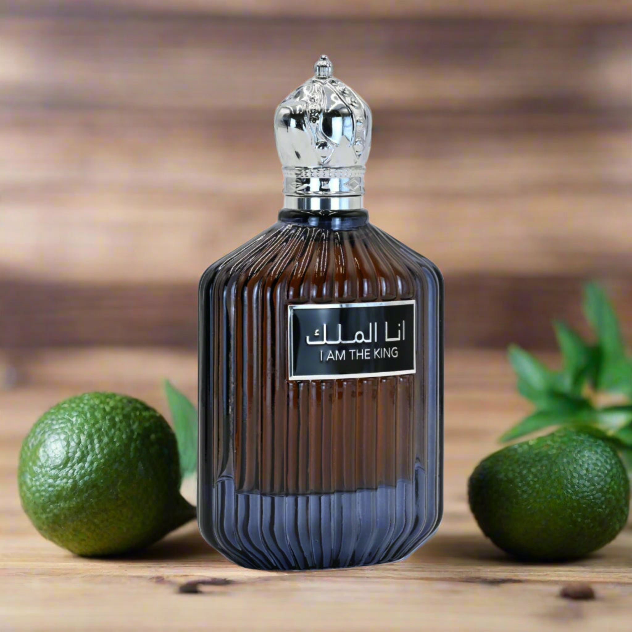 Perfume bottle labeled 'I AM THE KING' with green fruits on a wooden surface
