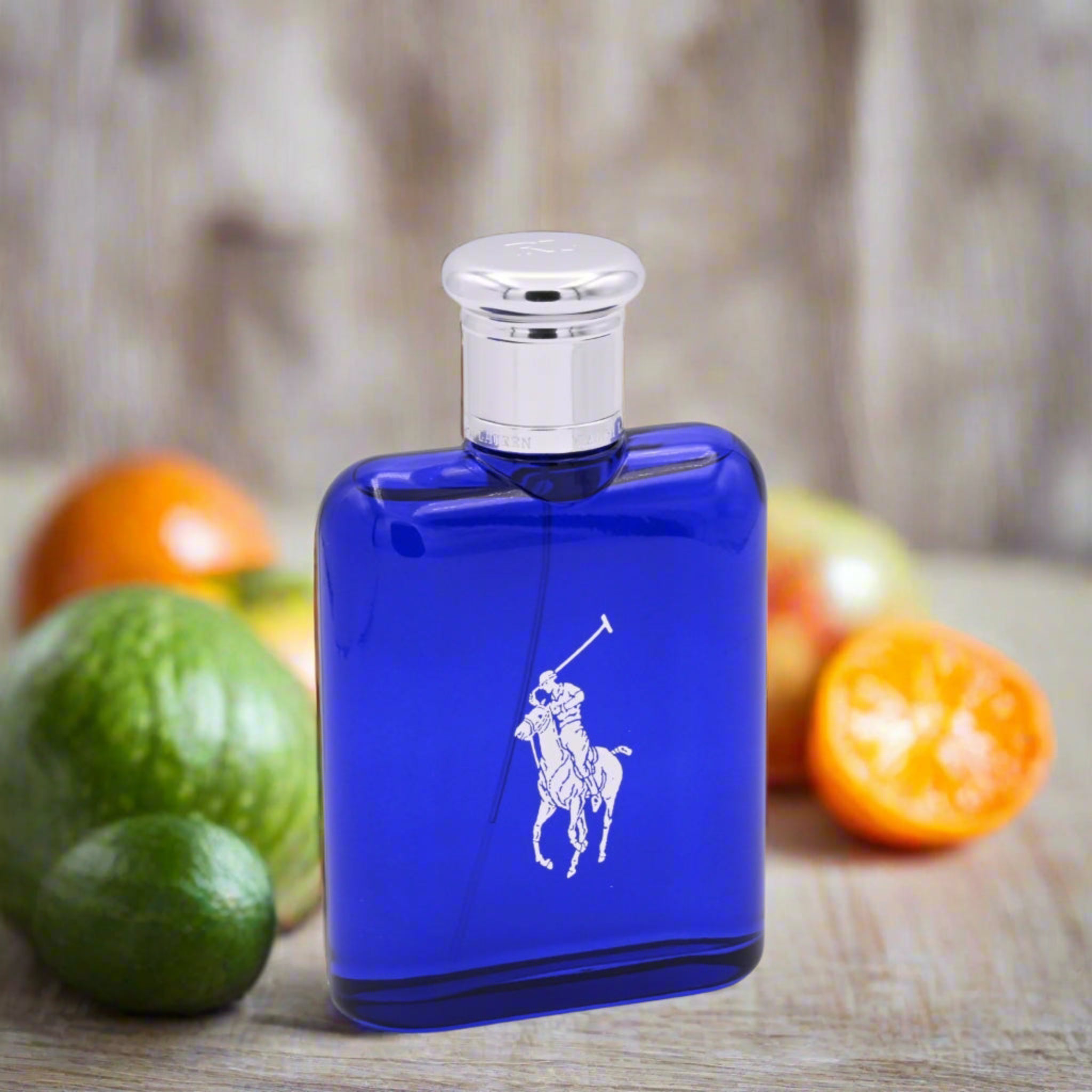 Blue Ralph Lauren cologne bottle with fruits on a wooden surface