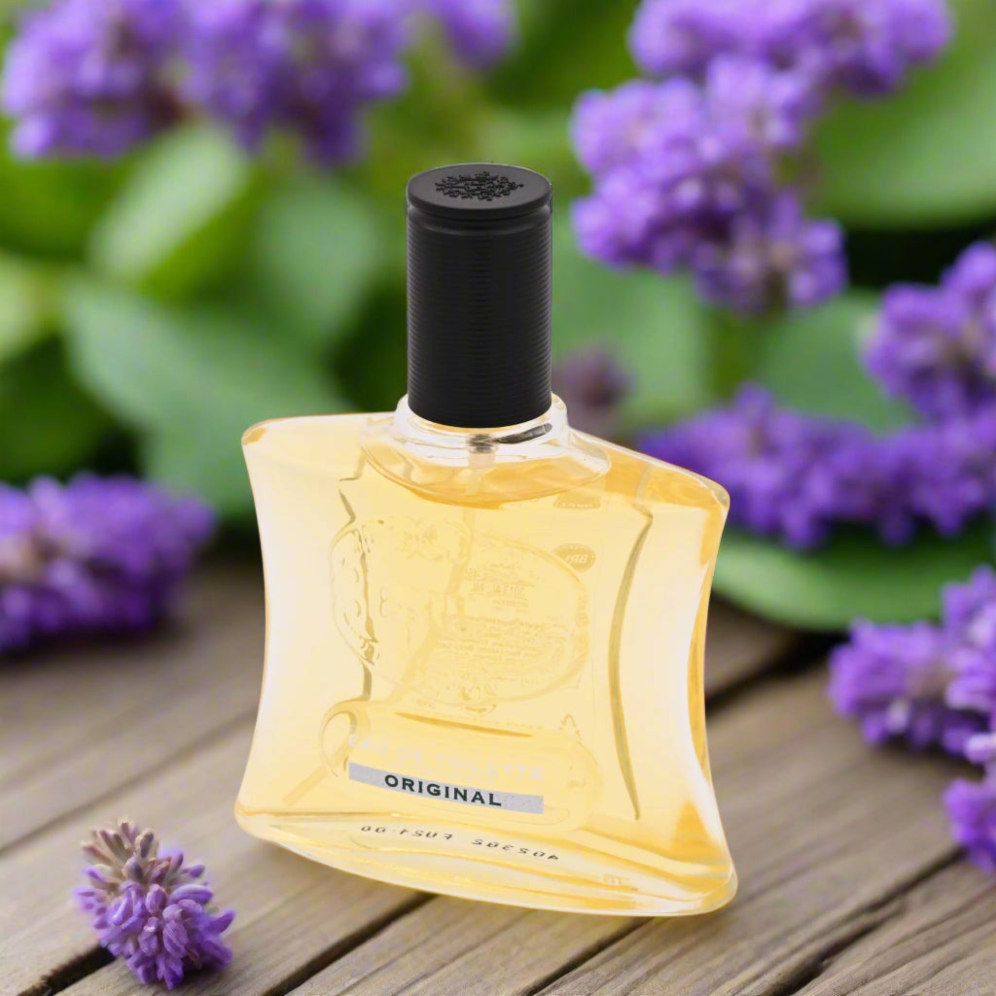 Perfume bottle with a black cap on a wooden surface surrounded by purple flowers