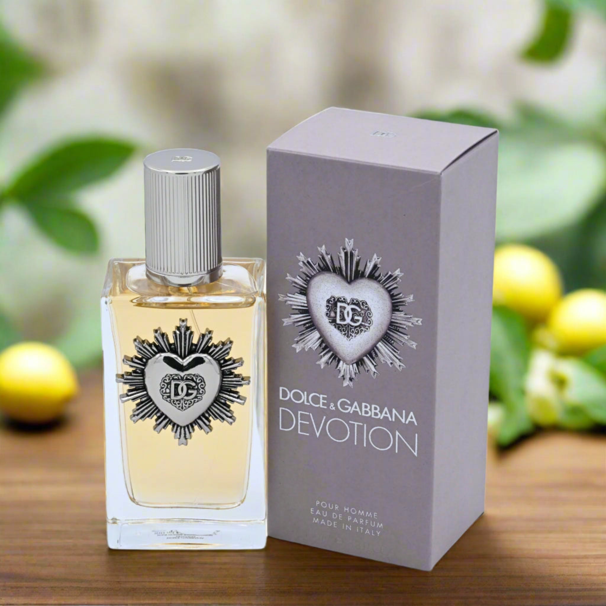 Dolce & Gabbana Devotion perfume bottle and packaging on a wooden surface with blurred greenery in the background