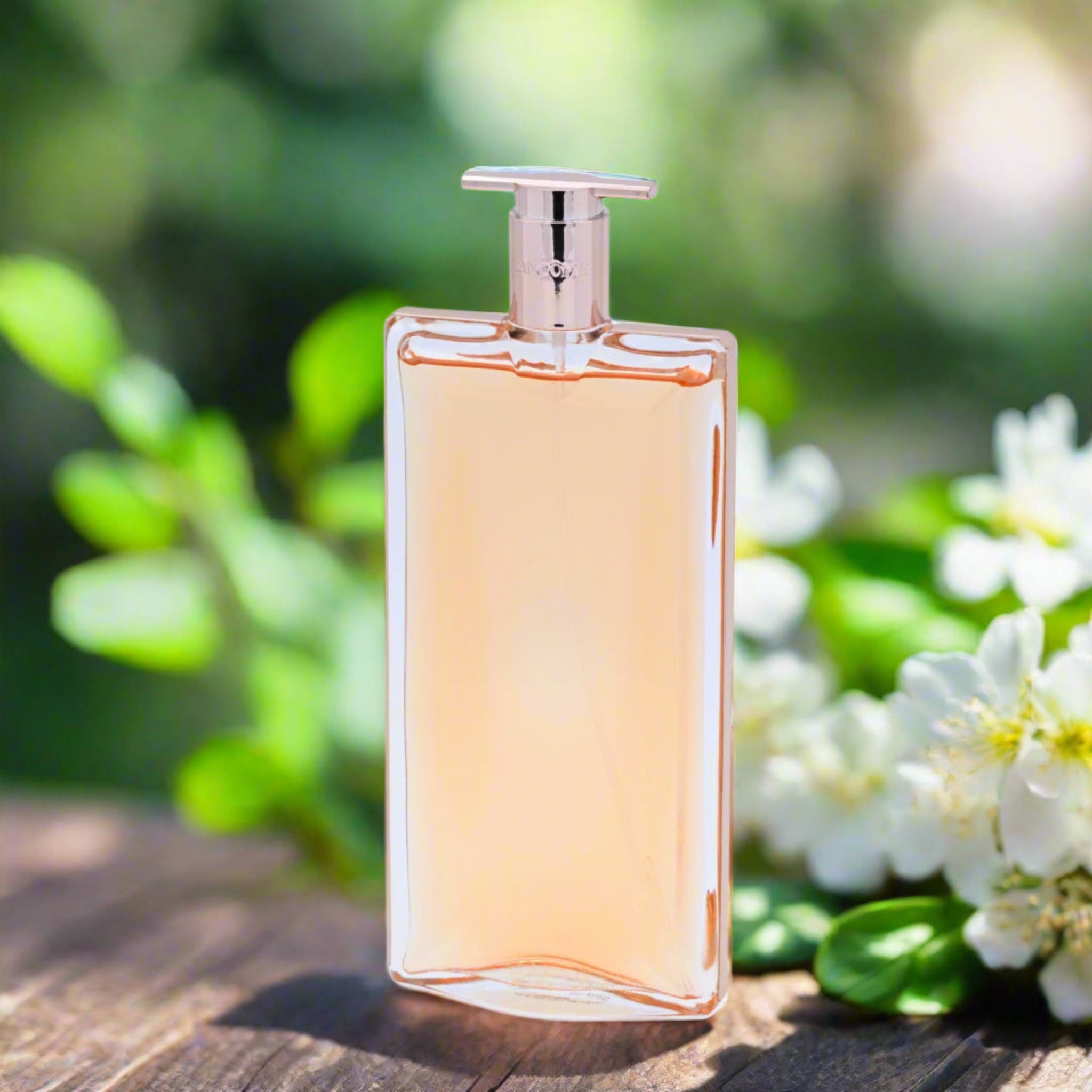 Perfume bottle on a wooden surface with greenery and flowers in the background