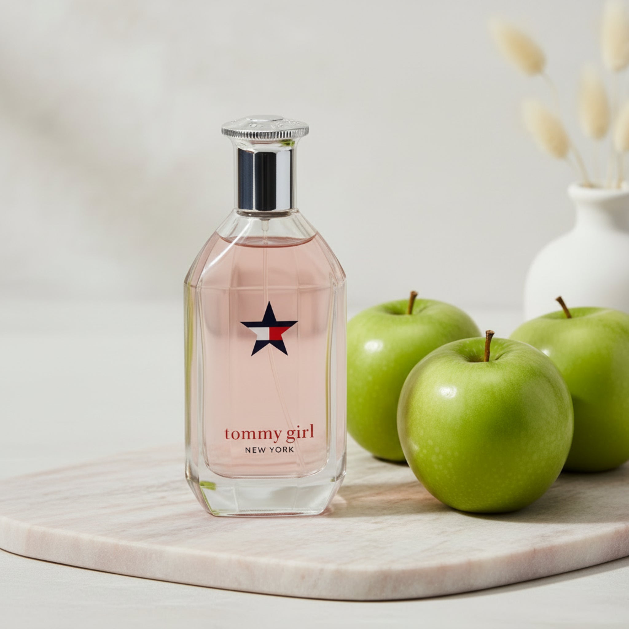 Tommy Girl perfume bottle with green apples on a wooden surface
