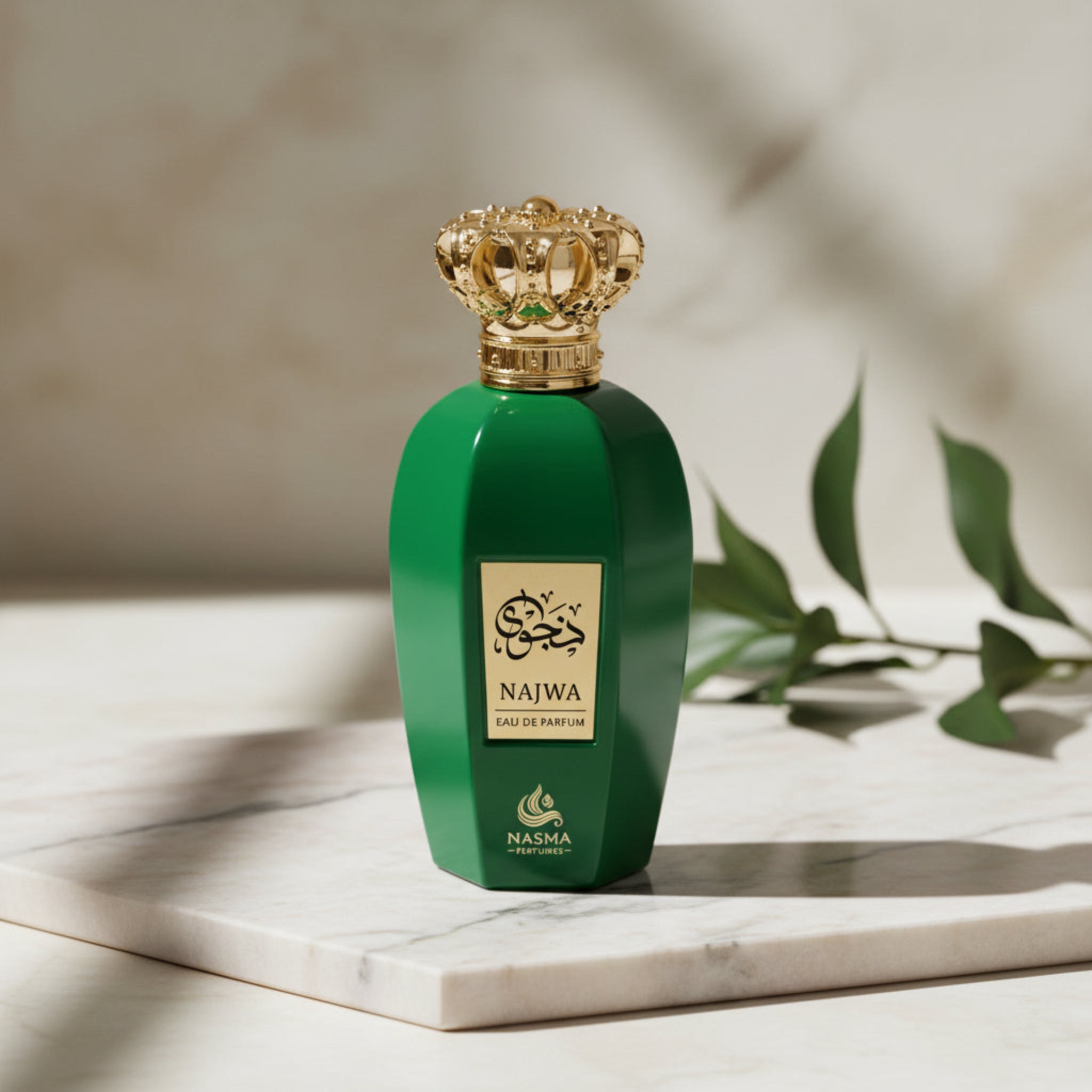 Green perfume bottle with gold cap on a marble surface with leaves in the background