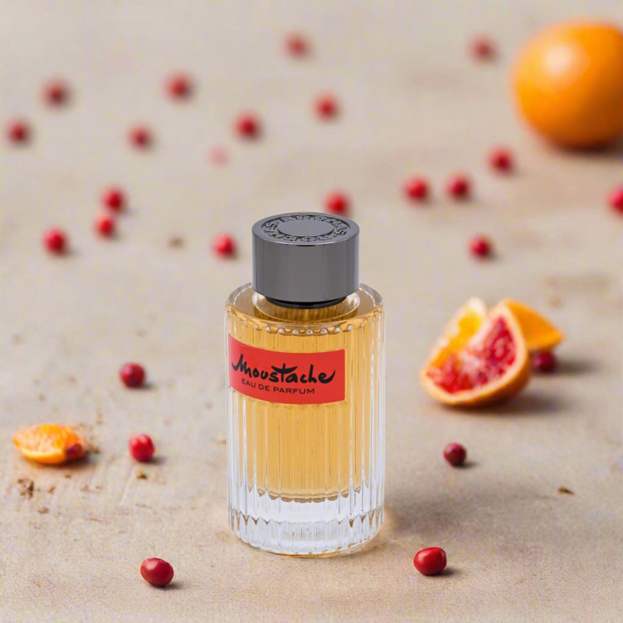 Perfume bottle with a red label on a beige surface with fruits