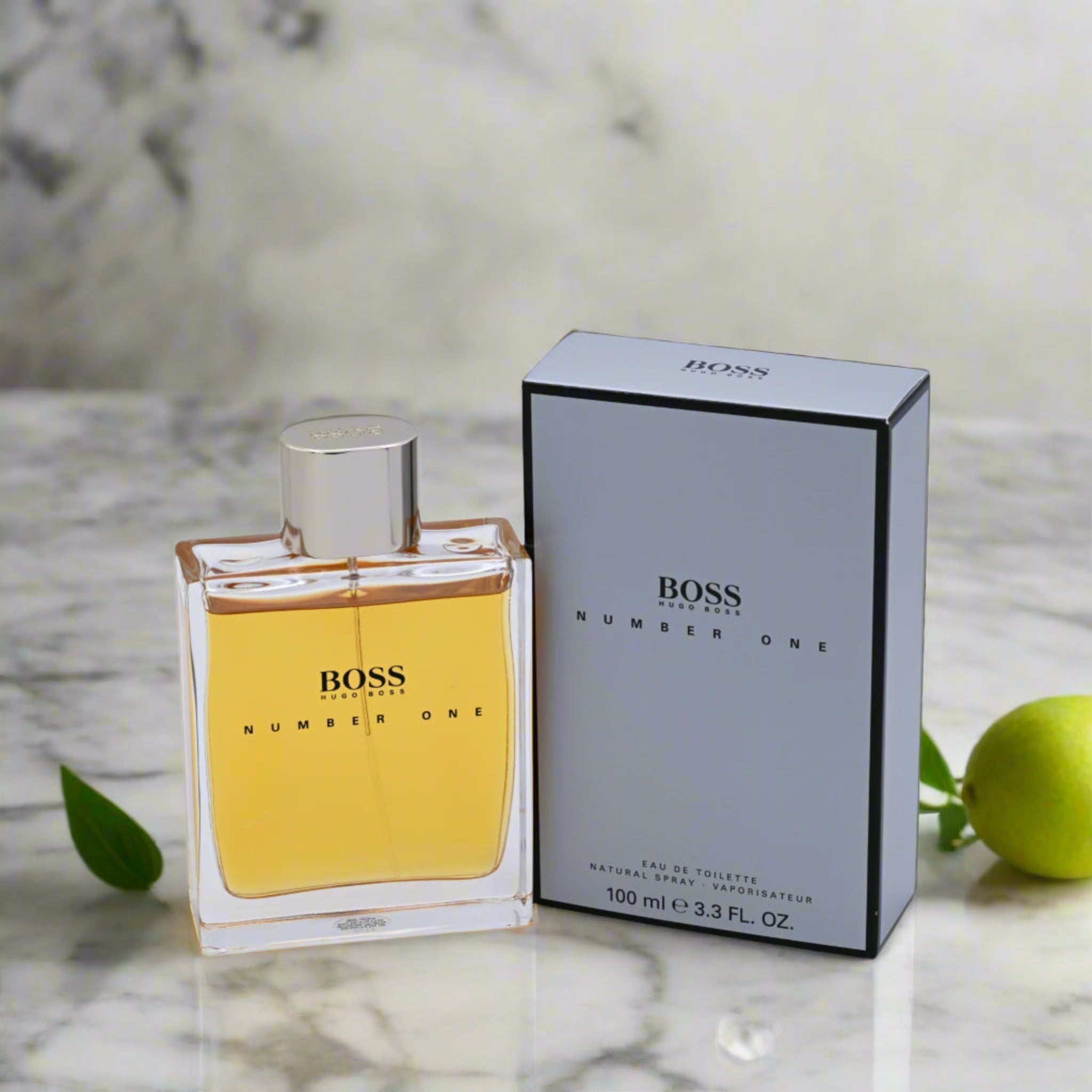 BOSS Number One perfume bottle and packaging on a marble surface with green leaves.