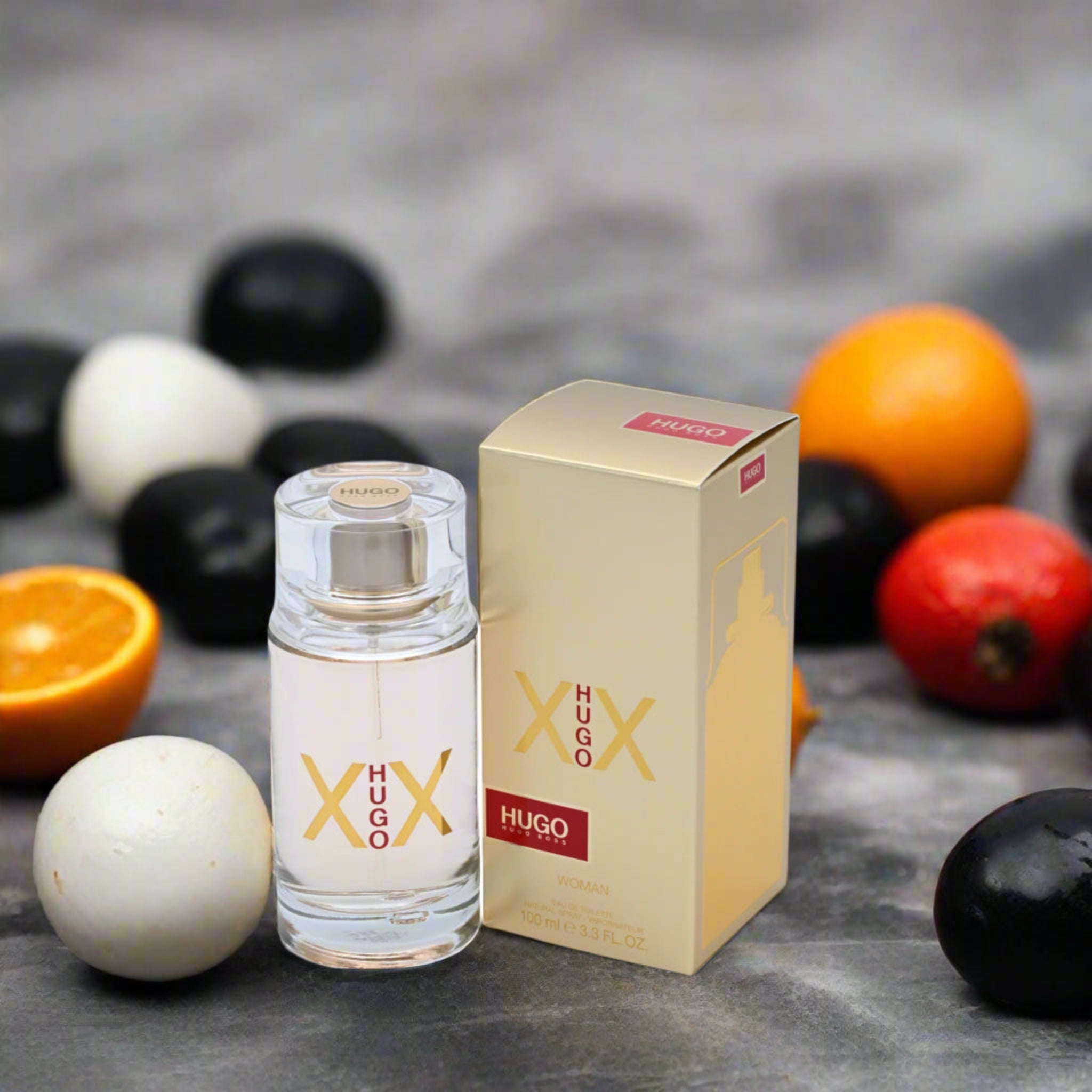Hugo Boss perfume bottle and packaging with fruits on a textured surface
