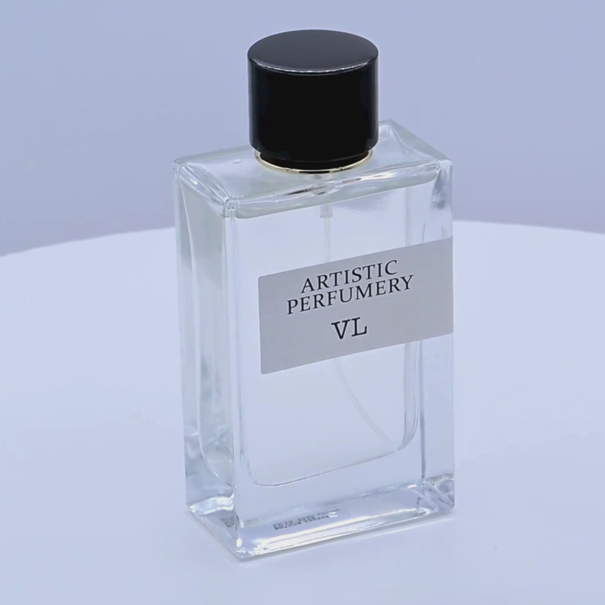 Clear perfume bottle with black cap labeled 'Artistic Perfumery VL' rotating on a white podium