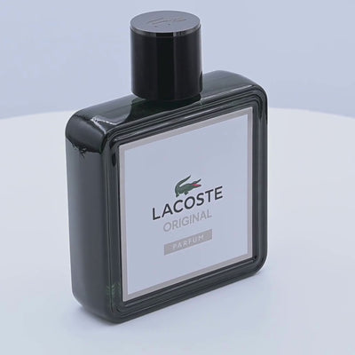 Black Lacoste Original Parfum bottle rotating on a white podium