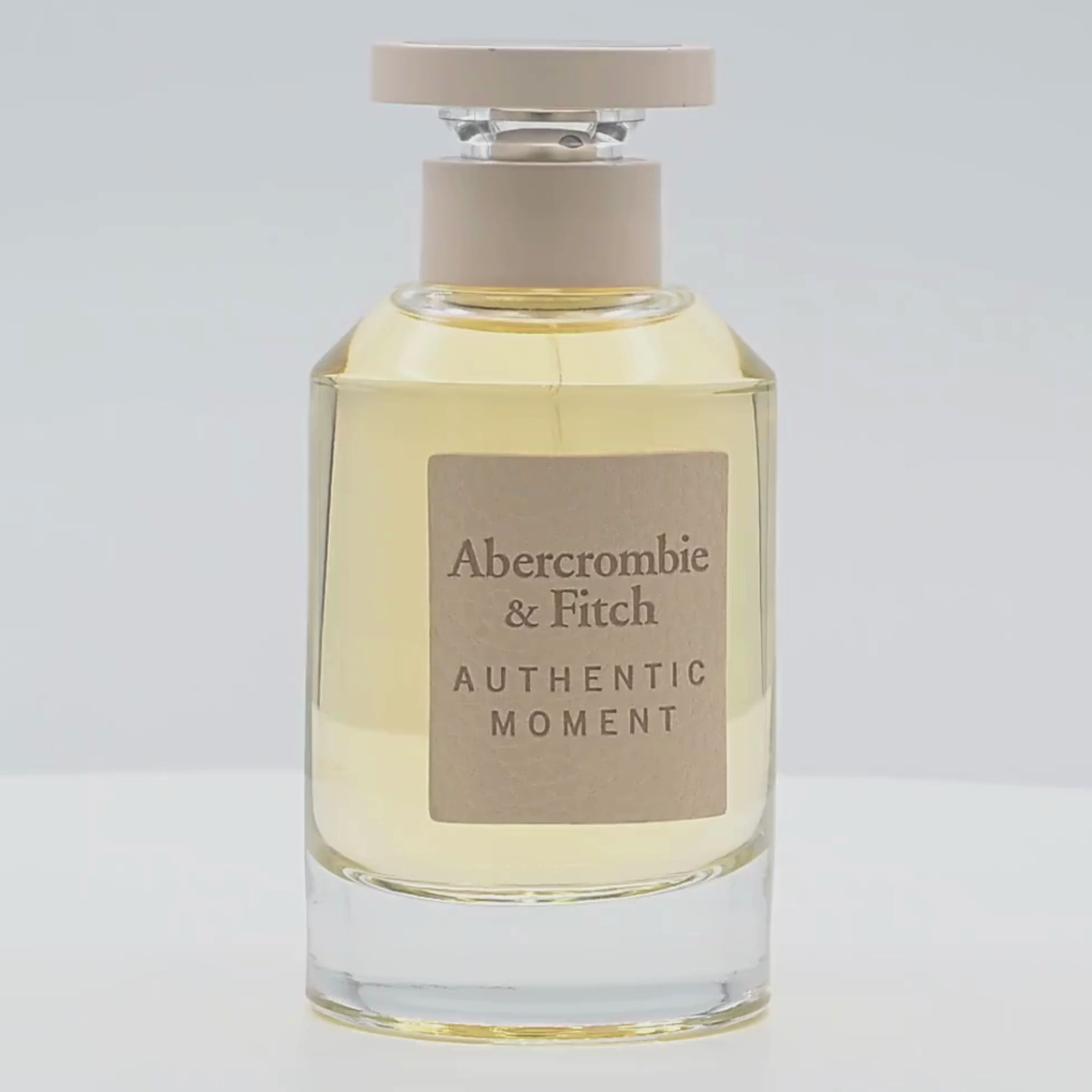 A bottle of Abercrombie & Fitch perfume rotating on a white podium