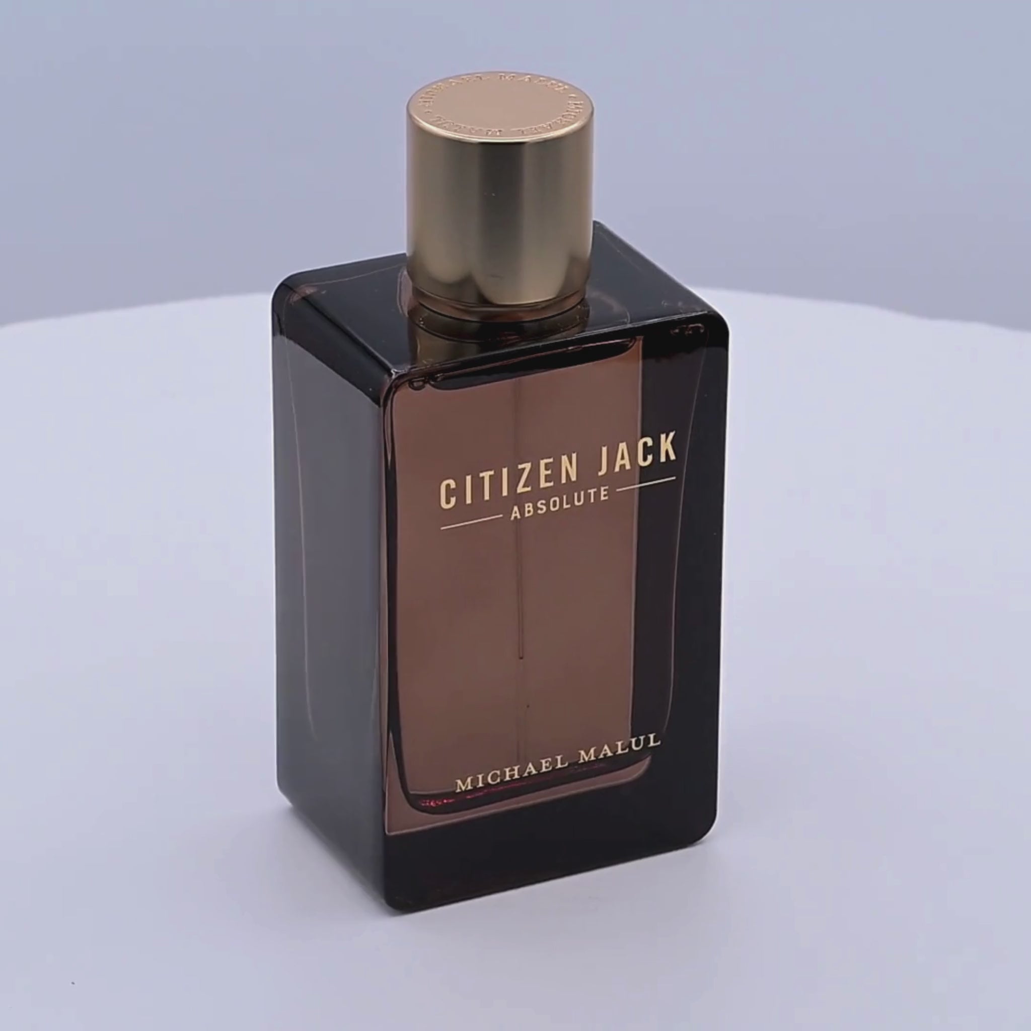 Perfume bottle labeled 'Citizen Jack Absolute' by Michael Malul rotating on a white podium