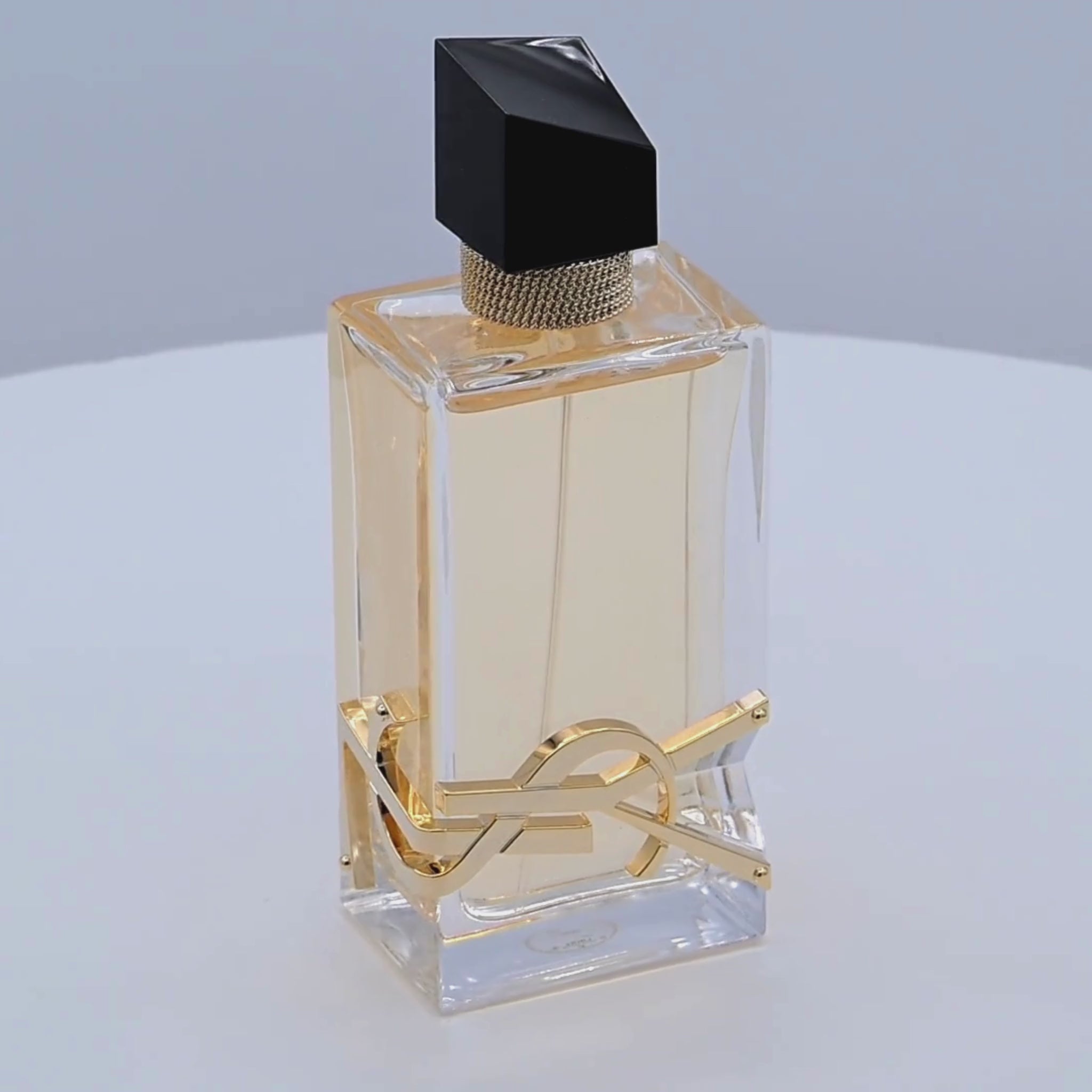 Yves Saint Laurent Libre perfume bottle rotating on a white podium