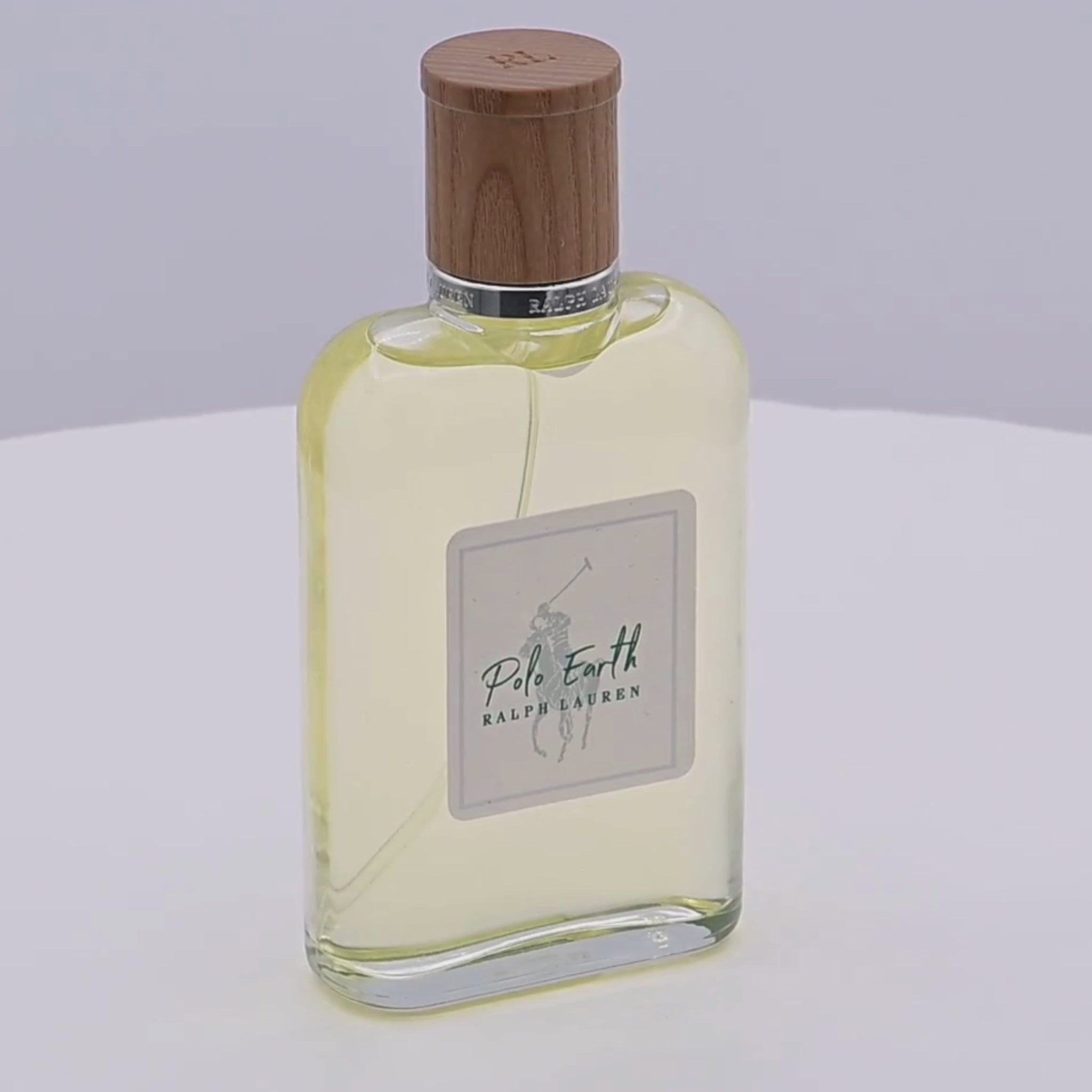 Ralph Lauren Polo Earth perfume bottle with wooden cap rotating on a white podium