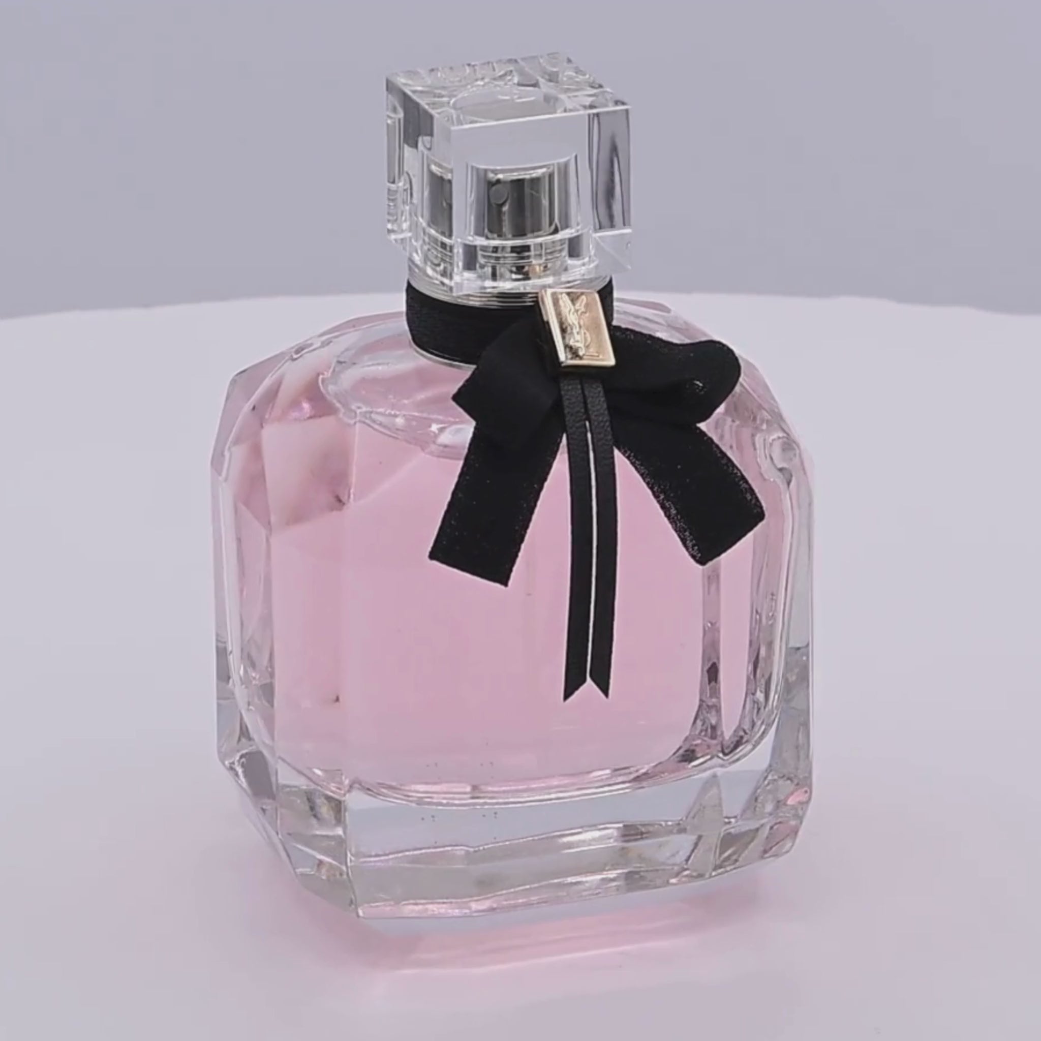 Pink perfume bottle rotating on a white podium