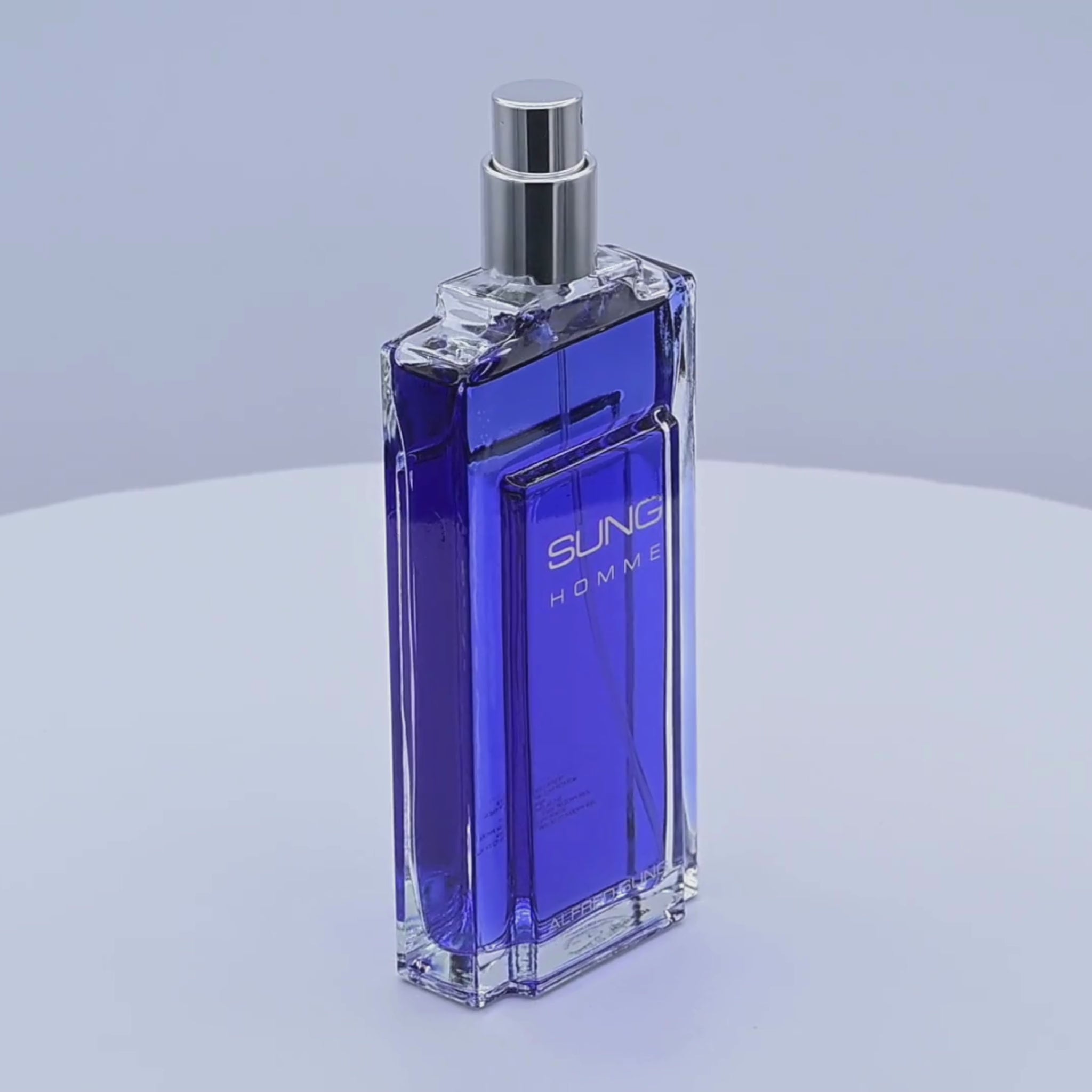 Blue perfume bottle labeled 'Sung Homme' rotating on a white podium