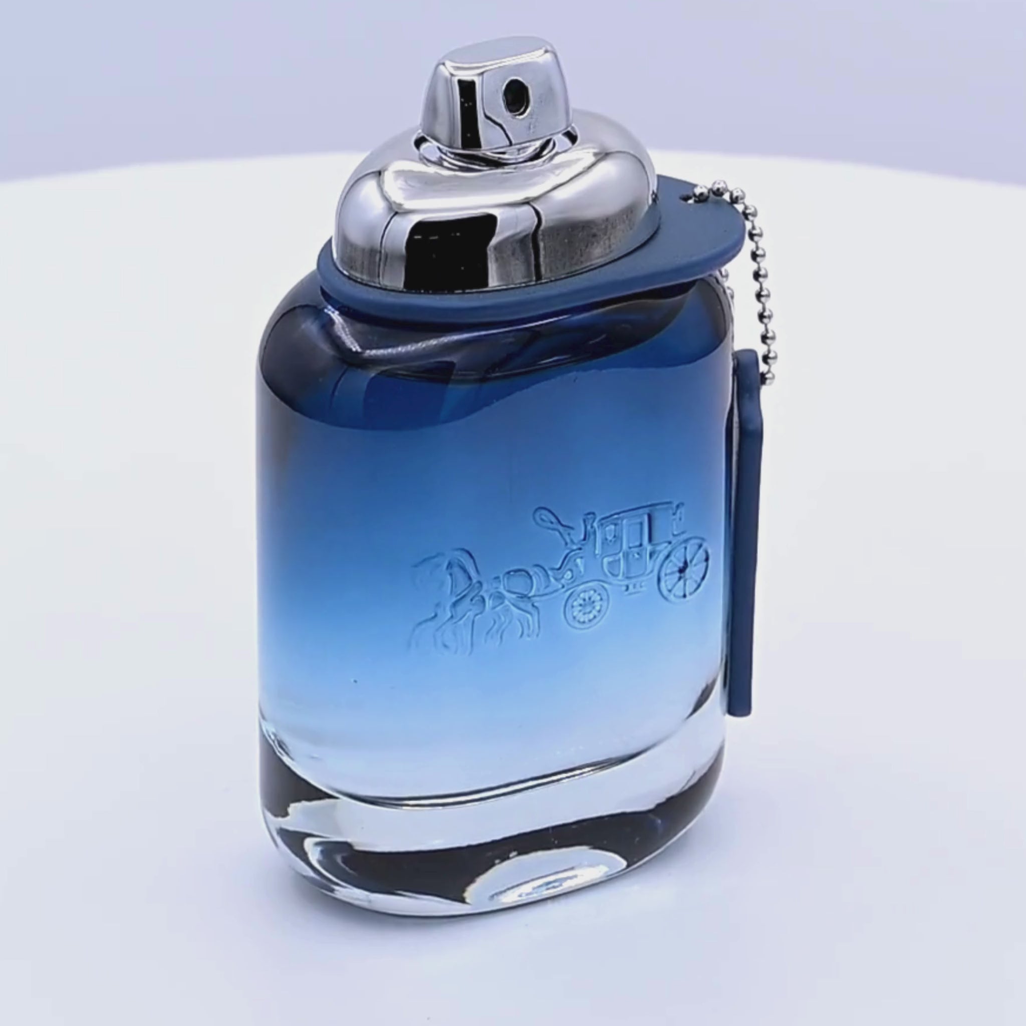 Coach New York Blue Eau de Toilette bottle rotating on a white podium