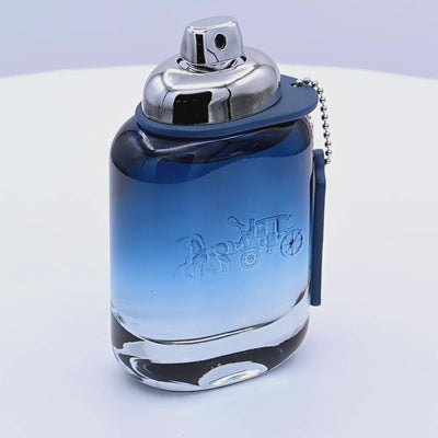 Coach New York Blue Eau de Toilette bottle rotating on a white podium