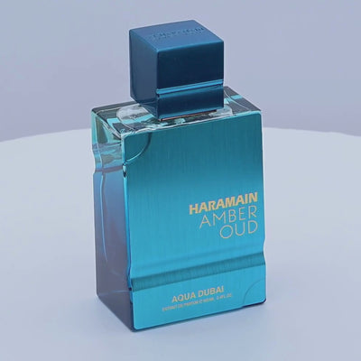 Blue perfume bottle with 'Haramain Amber Oud' text rotating on a white background 
