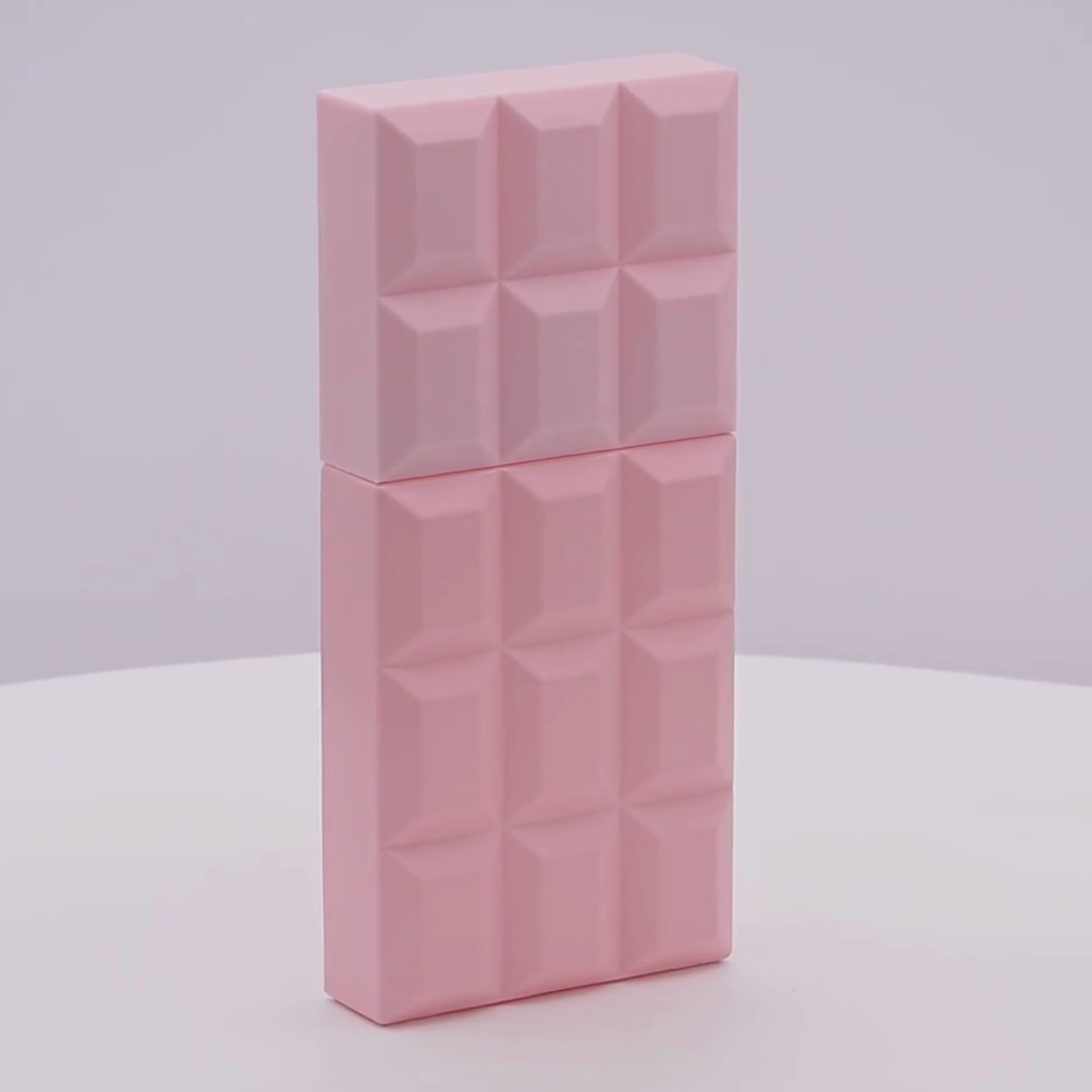 Pink perfume bottle with geometric pattern rotating on a white podium