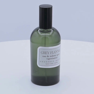 Green bottle of Grey Flannel eau de toilette spray by Geoffrey Beene rotating on a white podium