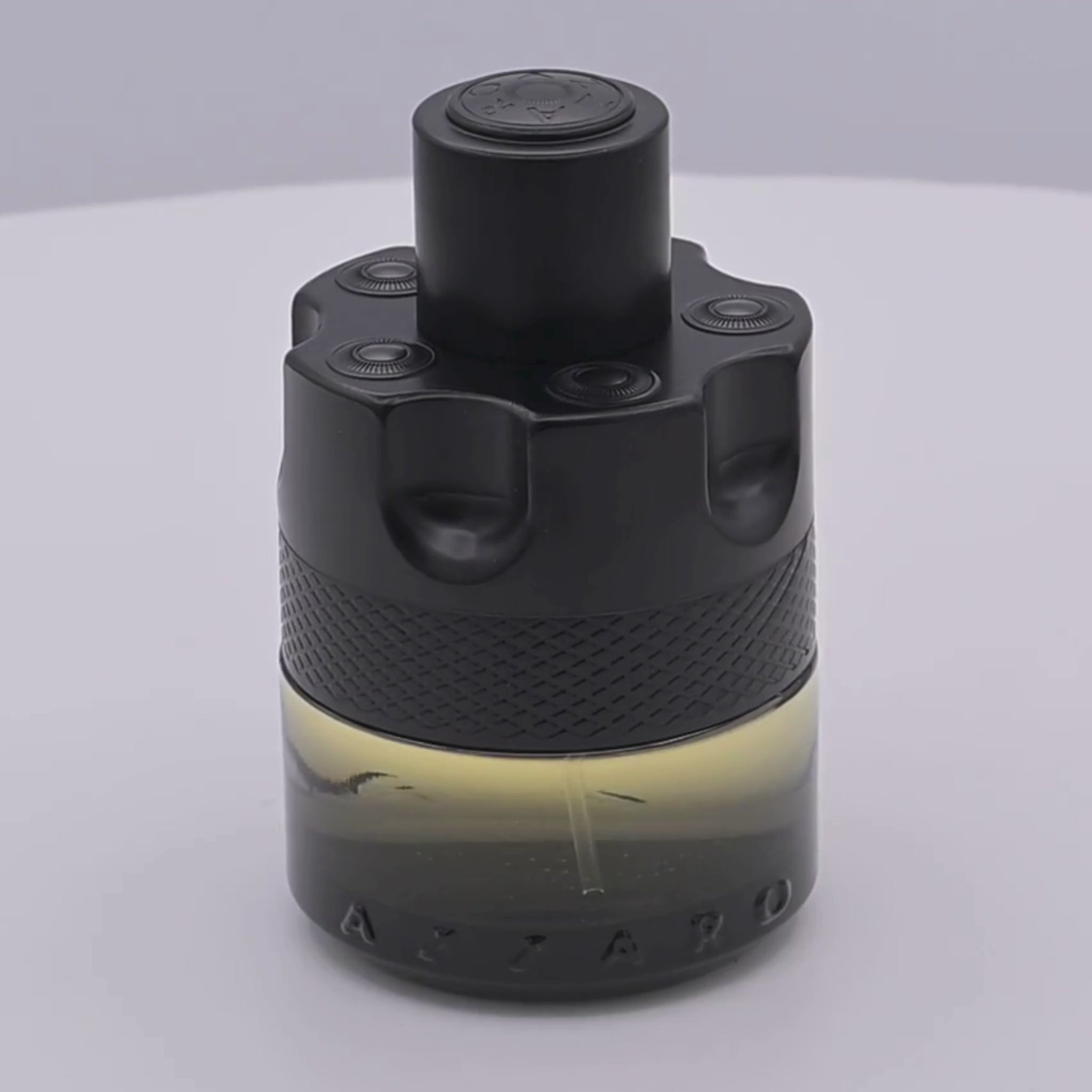 Azzaro The Most Wanted perfume bottle rotating on a white podium