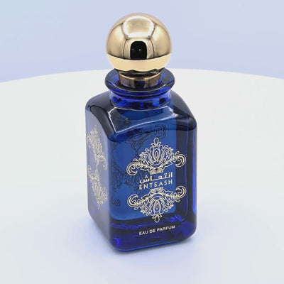 Blue perfume bottle with gold cap rotating on a white podium