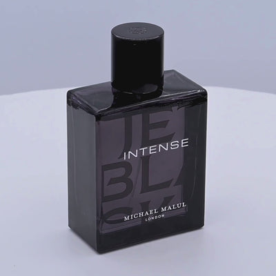 Black perfume bottle labeled 'INTENSE' by Michael Malul rotating on a white podium